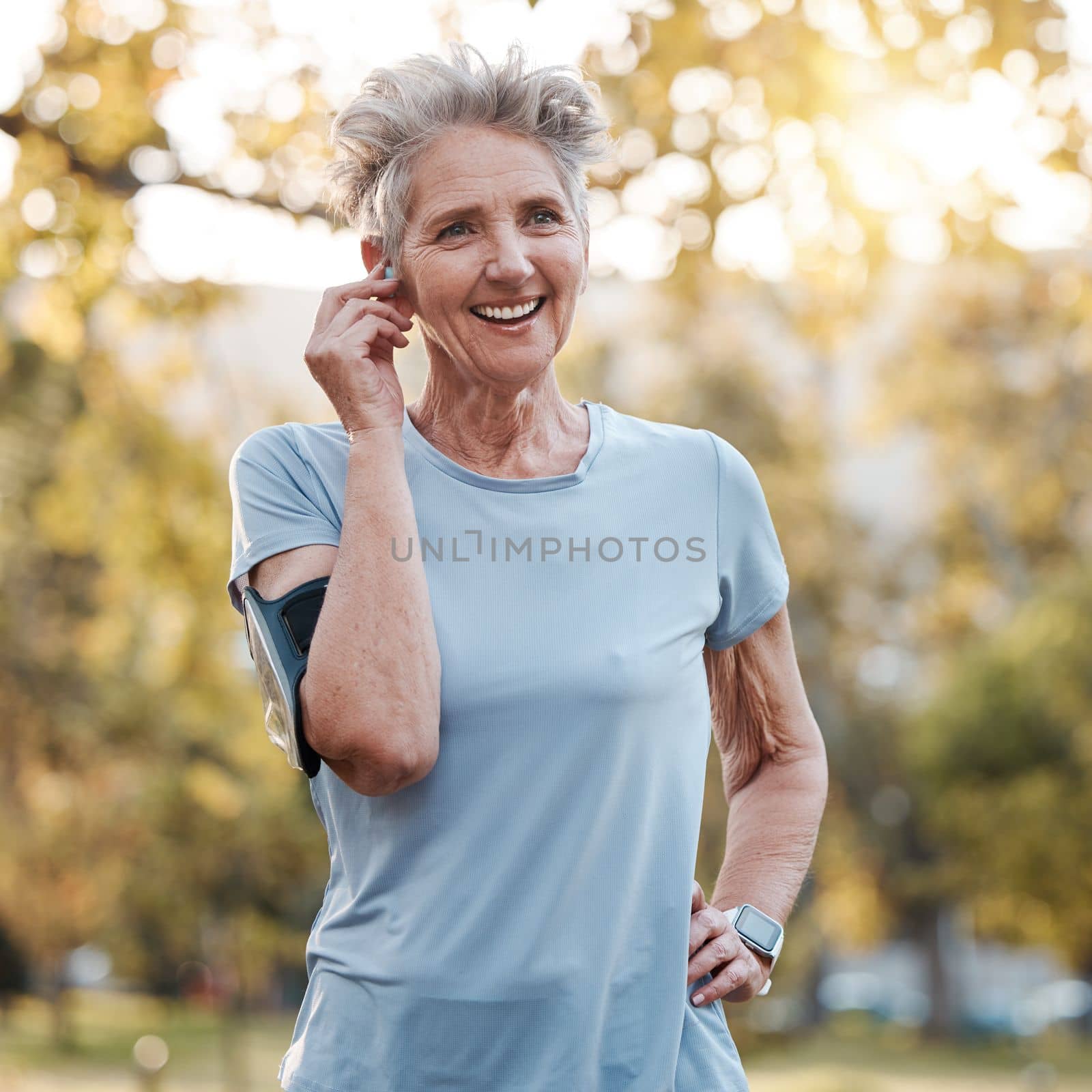 Senior woman, run outdoor and happy with music or audio podcast for lifestyle motivation, runner fitness and exercise workout. Elderly athlete, smile and training or running rest in nature park by YuriArcurs