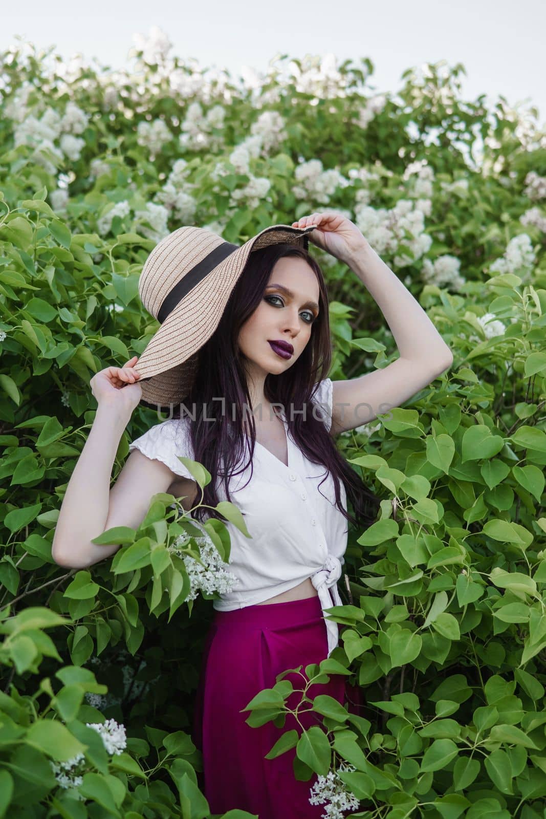 A fashionable girl with dark hair, a spring portrait in lilac tones in summer. Bright professional makeup