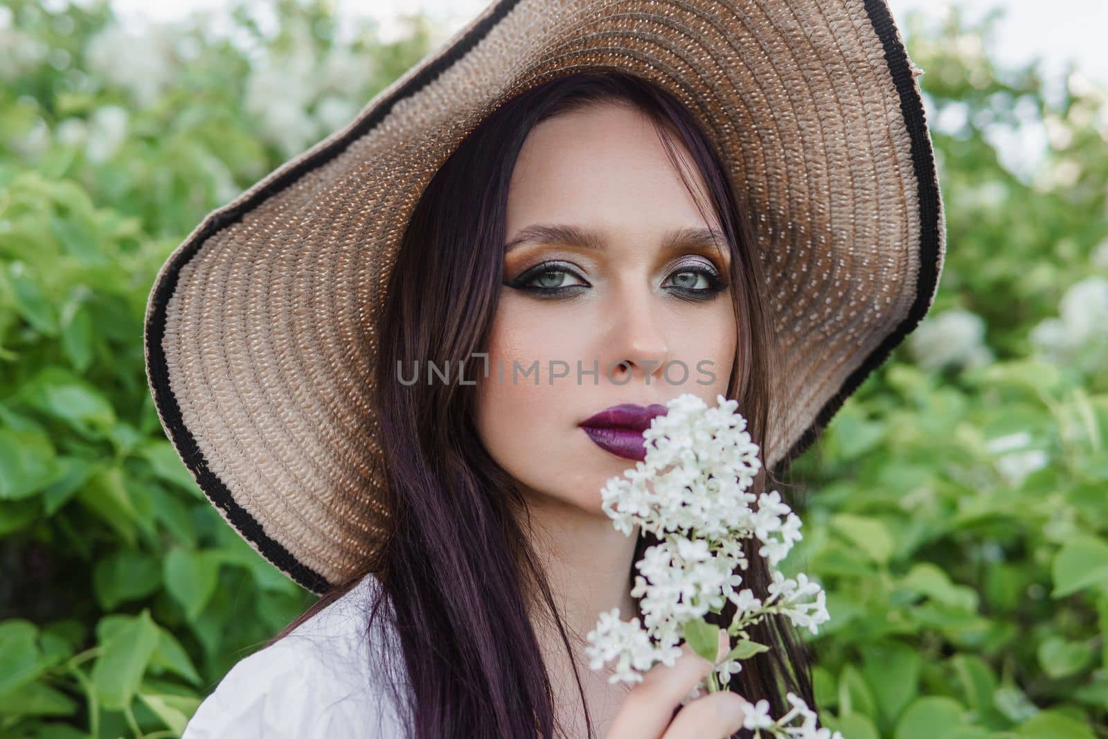 A fashionable girl with dark hair, a spring portrait in lilac tones in summer. Bright professional makeup