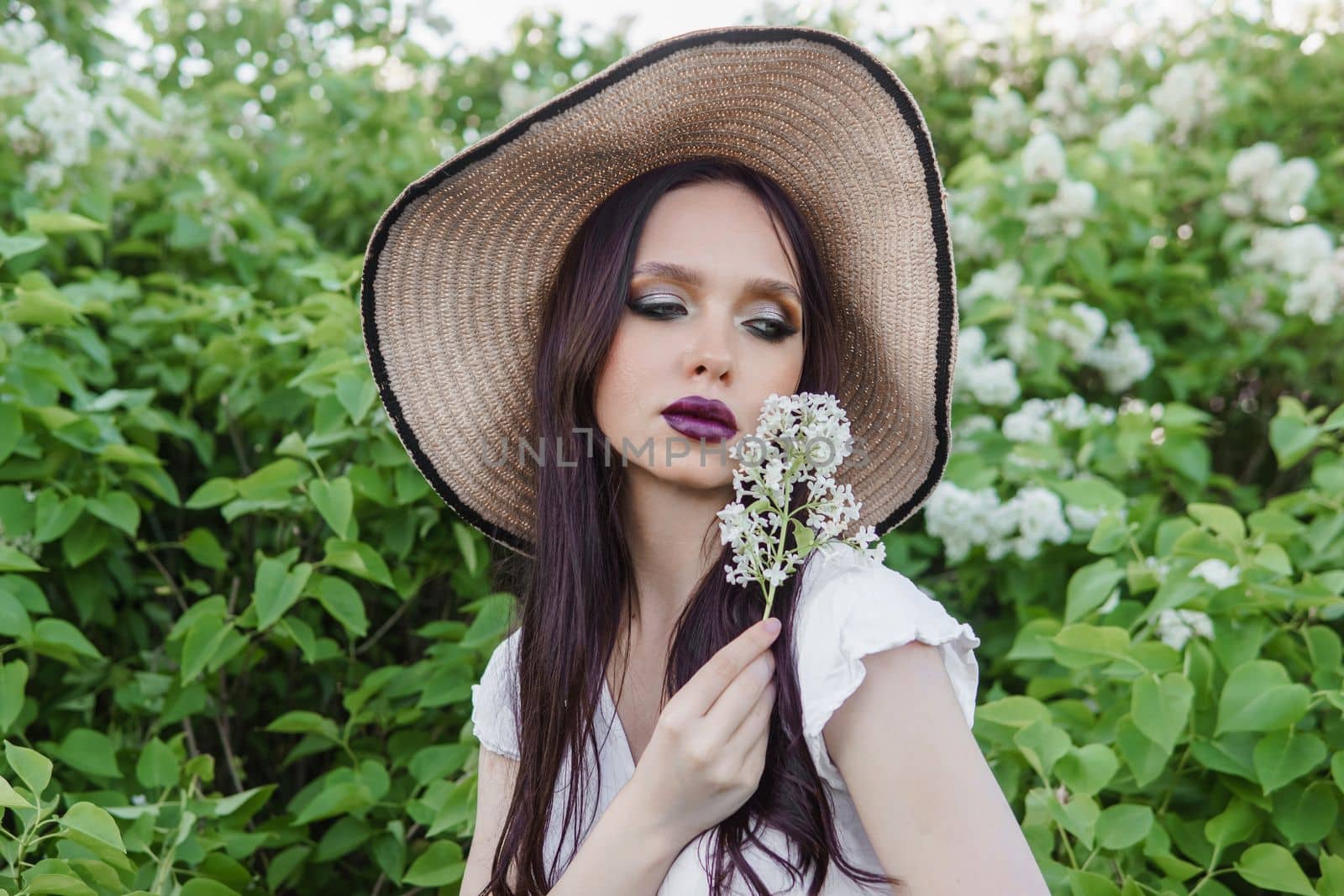 A fashionable girl with dark hair, a spring portrait in lilac tones in summer. Bright professional makeup