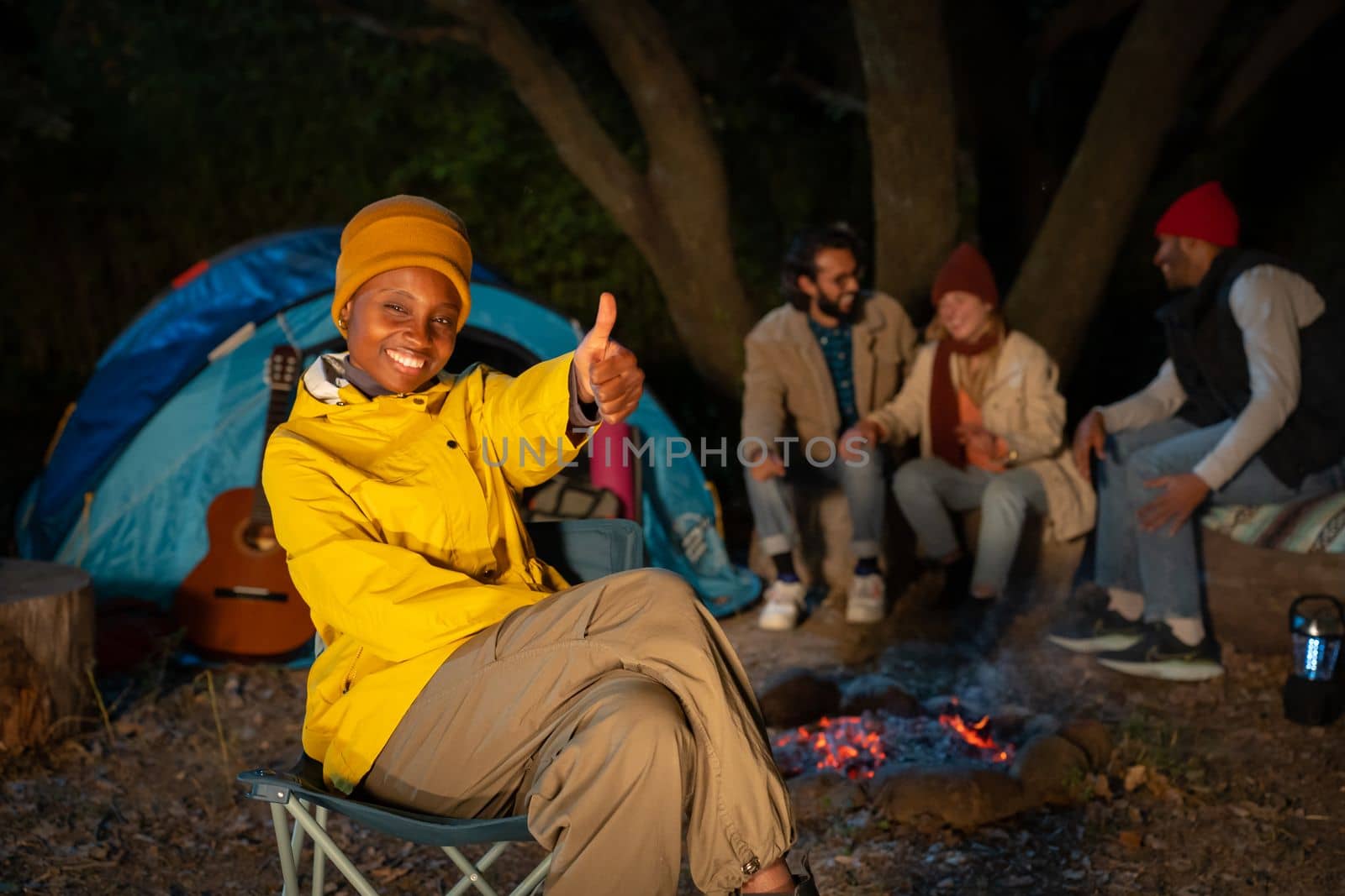 Group of friends with guitar near the bonfire and camping outdoors in the afternoon. Travel concept by PaulCarr