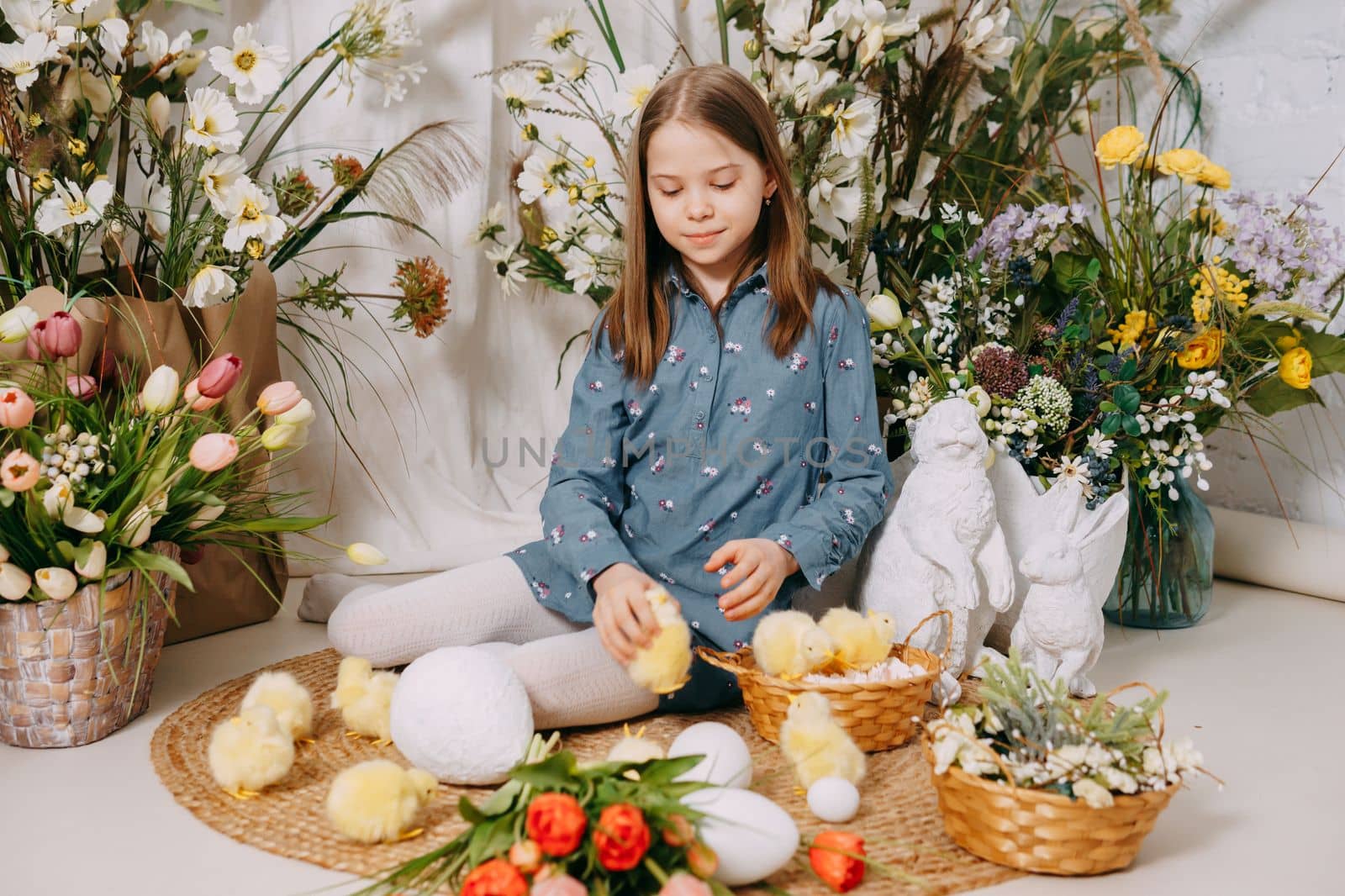 Two girls in a beautiful Easter photo zone with flowers, eggs, chickens and Easter bunnies. Happy Easter holiday. by Annu1tochka