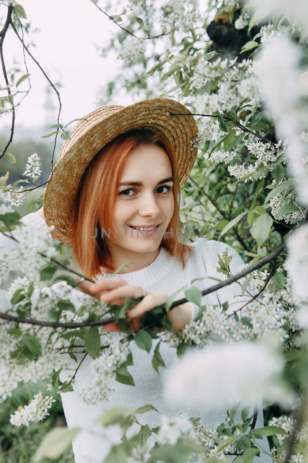 Portrait of a woman in a straw hat in a cherry blossom. Free outdoor recreation, spring blooming garden