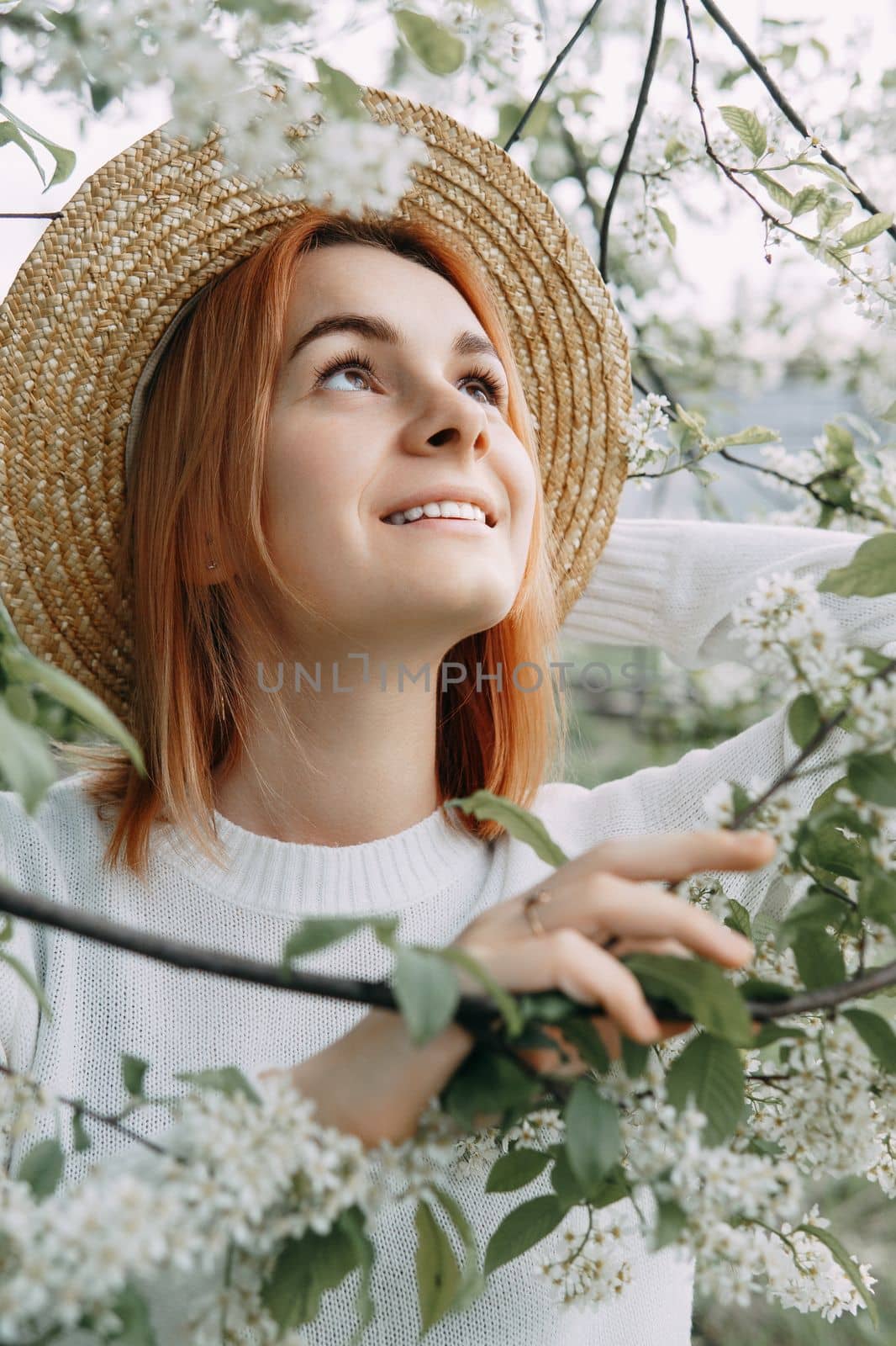 Portrait of a woman in a straw hat in a cherry blossom. Free outdoor recreation, spring blooming garden
