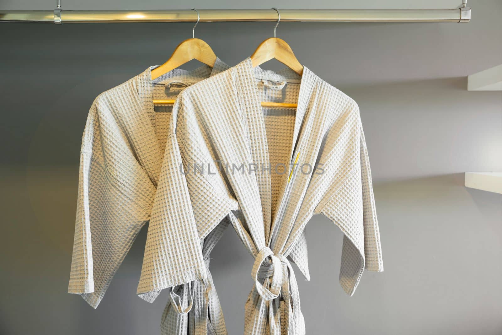 Grey colored bathrobe on the hanger in the room at hotel.