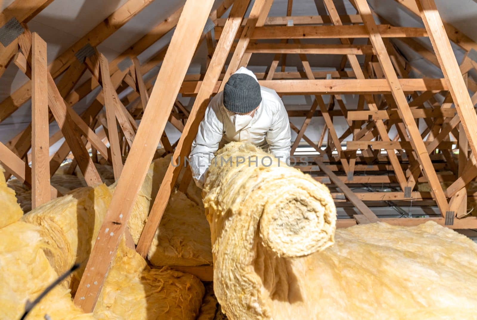 man insulates the roof and ceiling of the house with glass wool by Edophoto