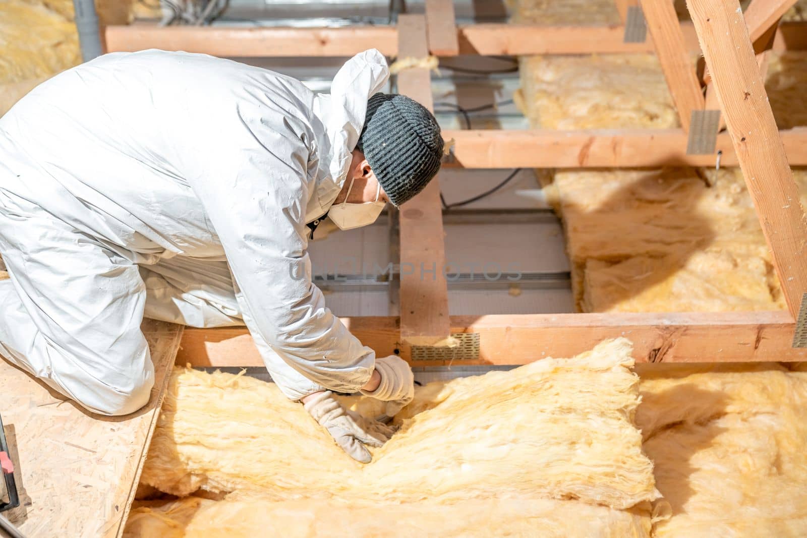 man insulates the roof and ceiling of the house with glass wool by Edophoto