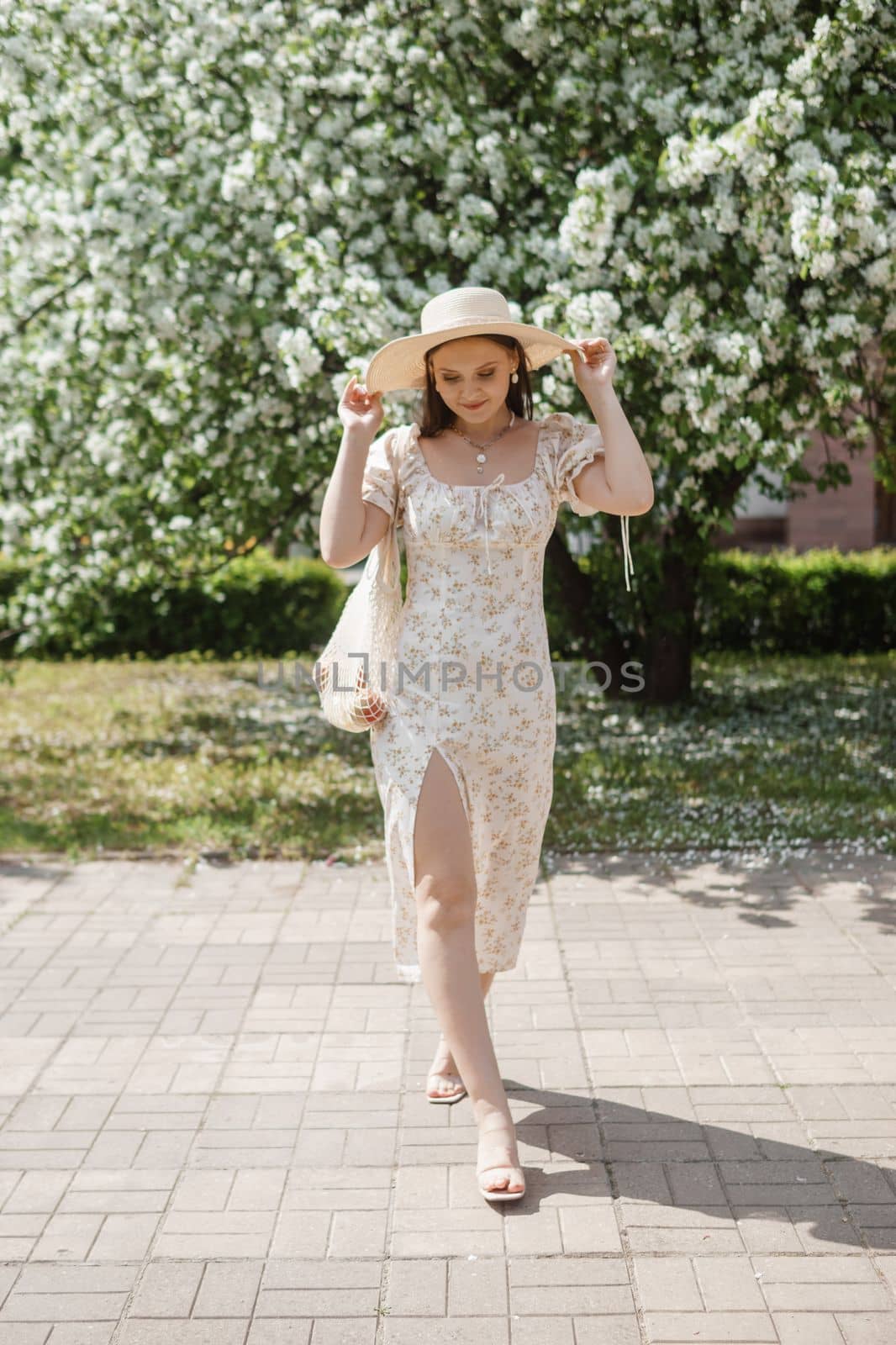 An attractive long-haired woman walks in the spring in the park of blooming apple trees. Spring portrait of a woman