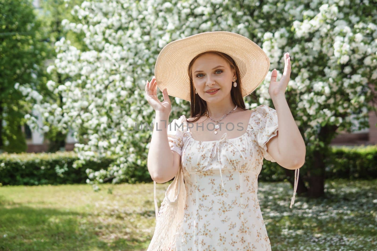 An attractive long-haired woman walks in the spring in the park of blooming apple trees. Spring portrait of a woman