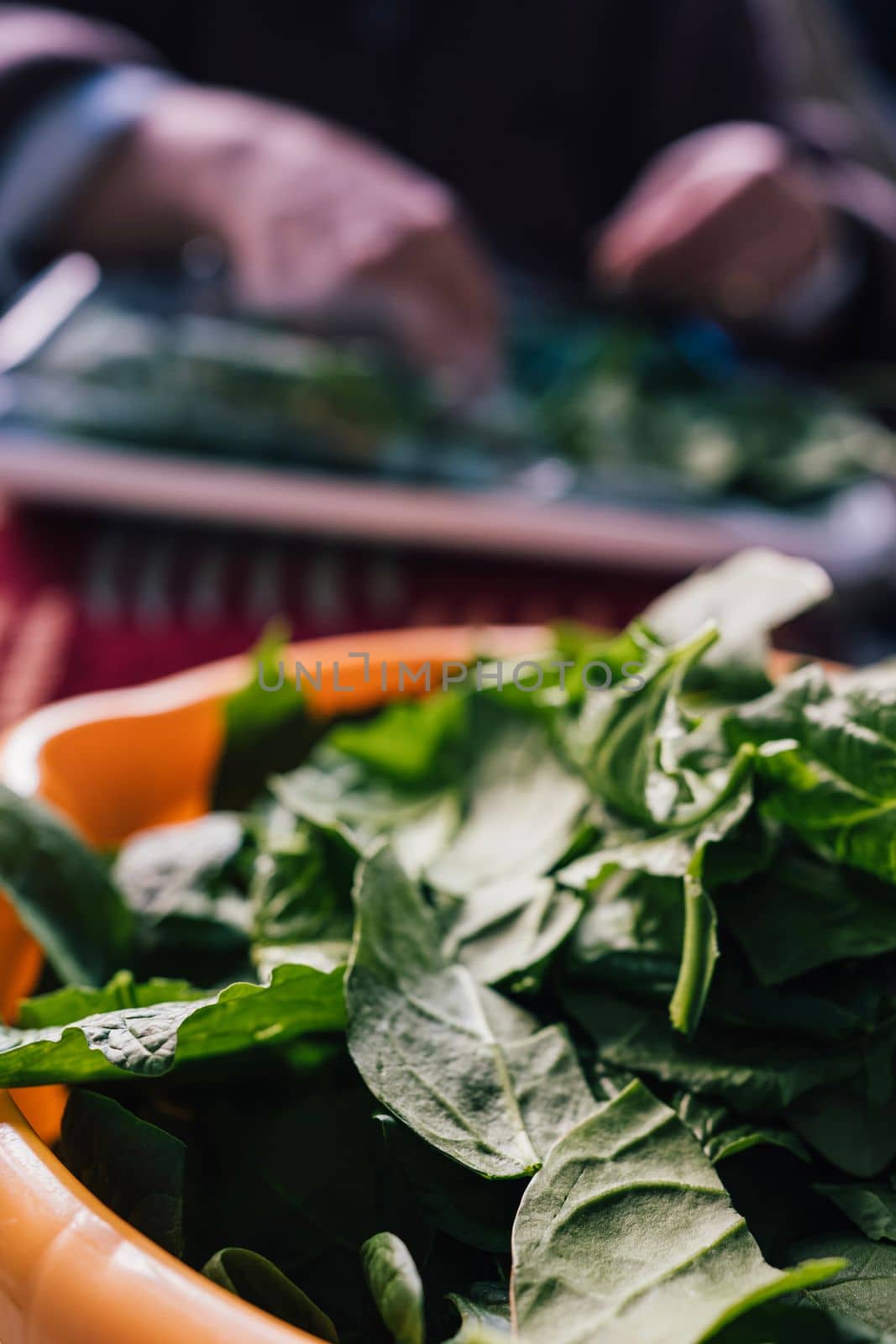 Close up of clean and selected fresh spinach leaves in orange bowl. Healthy lifestyle concept.