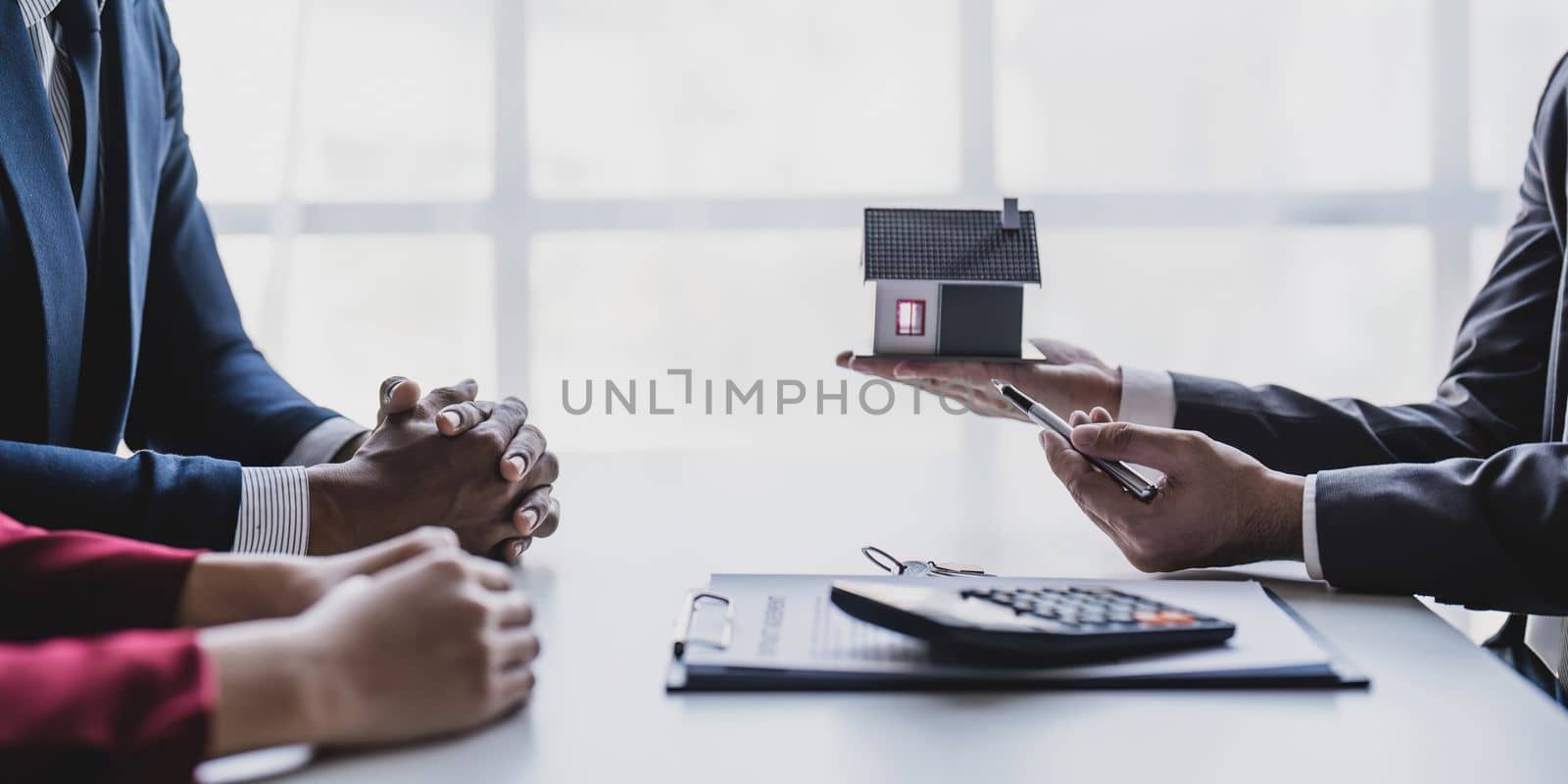 Real estate agent gives key to smiling clients. Happy couple signs papers and takes key to new home. Concept of young family making dream come true, buying house or getting apartment mortgage approval.