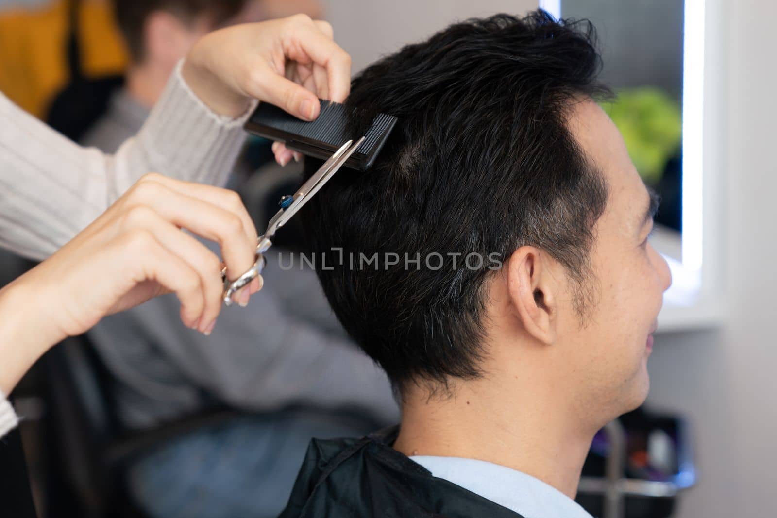 Qualified female barber make haircut for male customer in qualified hair salon. by biancoblue