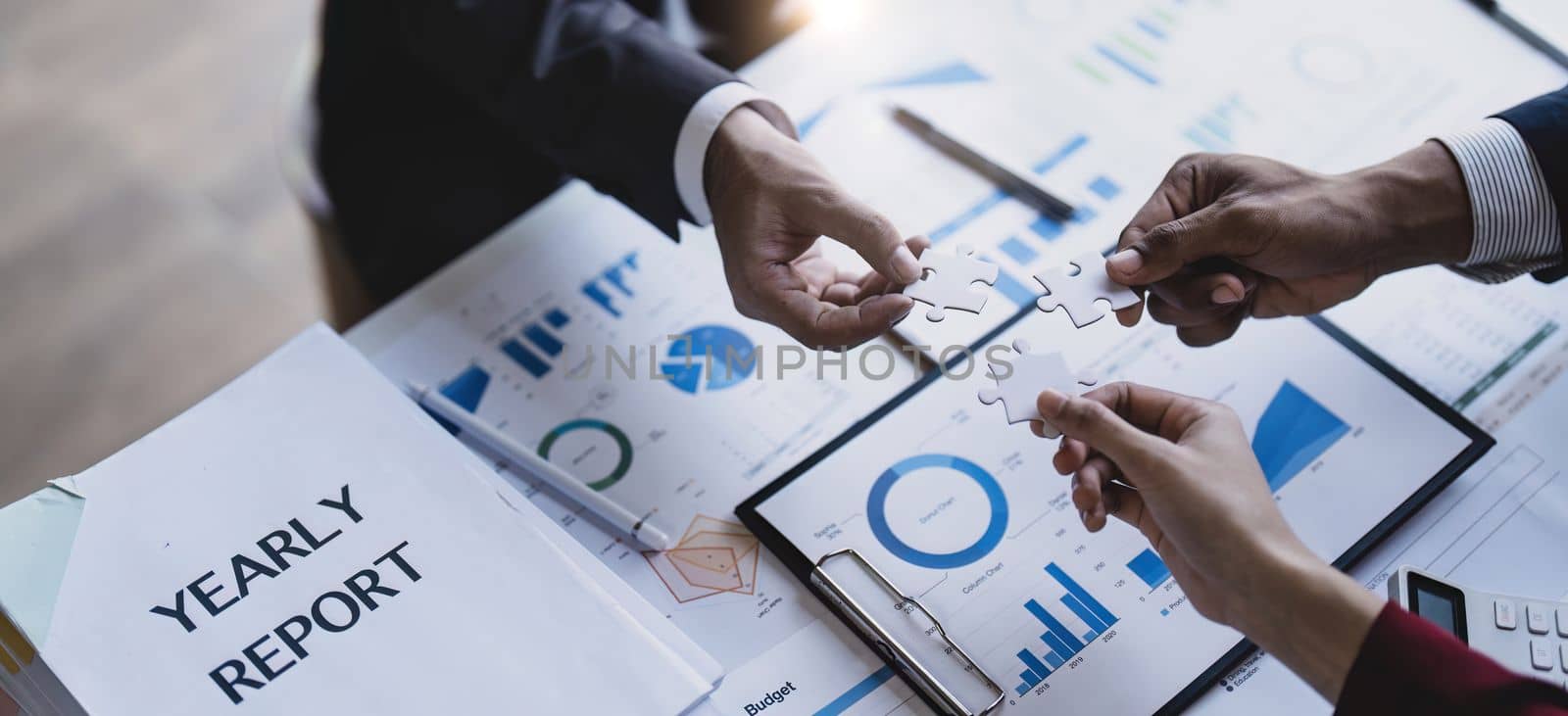 Business people with jigsaw puzzle pieces in office, Successful teamwork and partnership concept. hands holding pieces of white jigsaw puzzle.