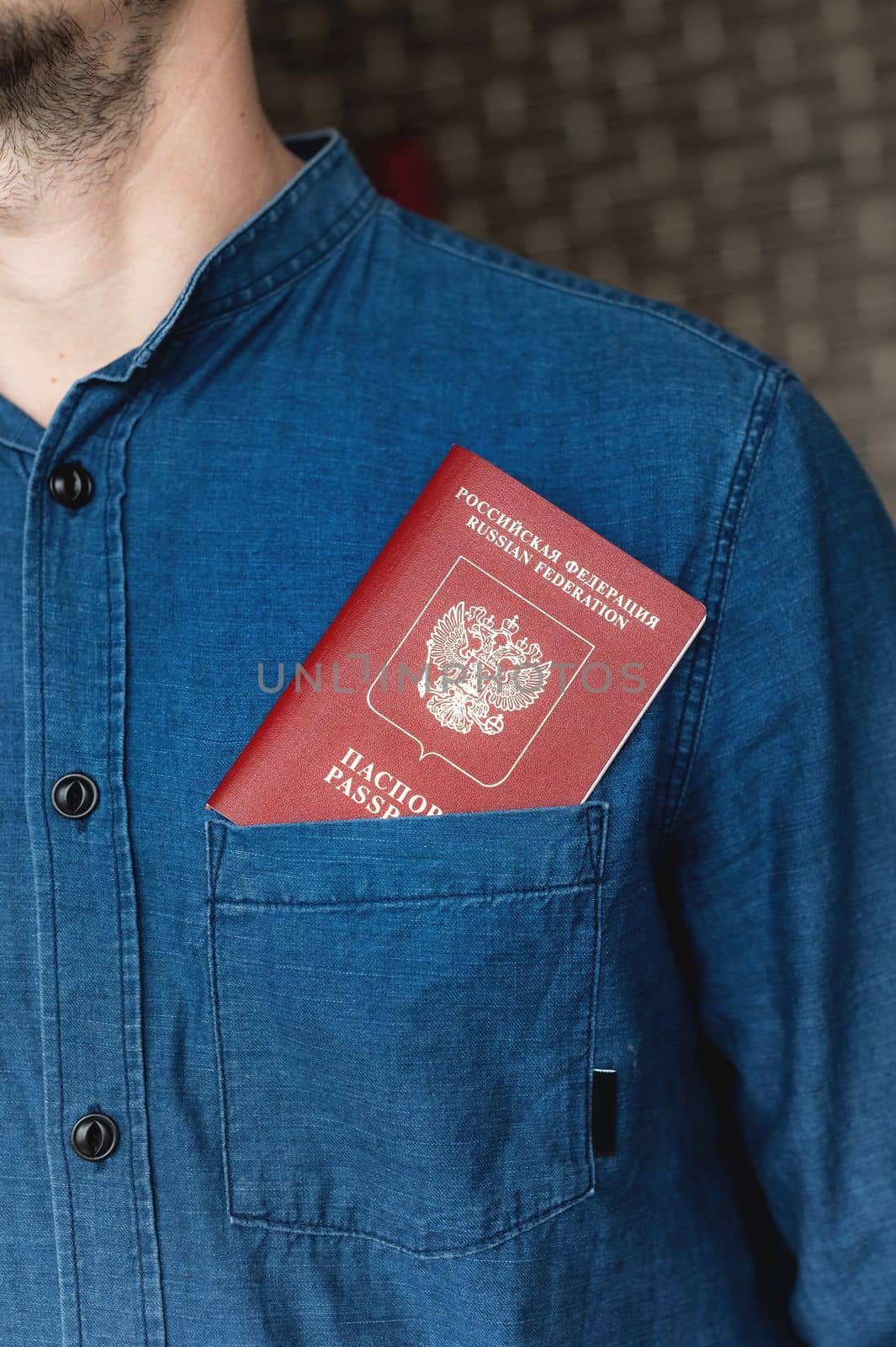 Close-up of a man in a blue shirt, a passport peeks out of his pocket. Tourism and travel concept. Selective focus, unrecognizable person by yanik88