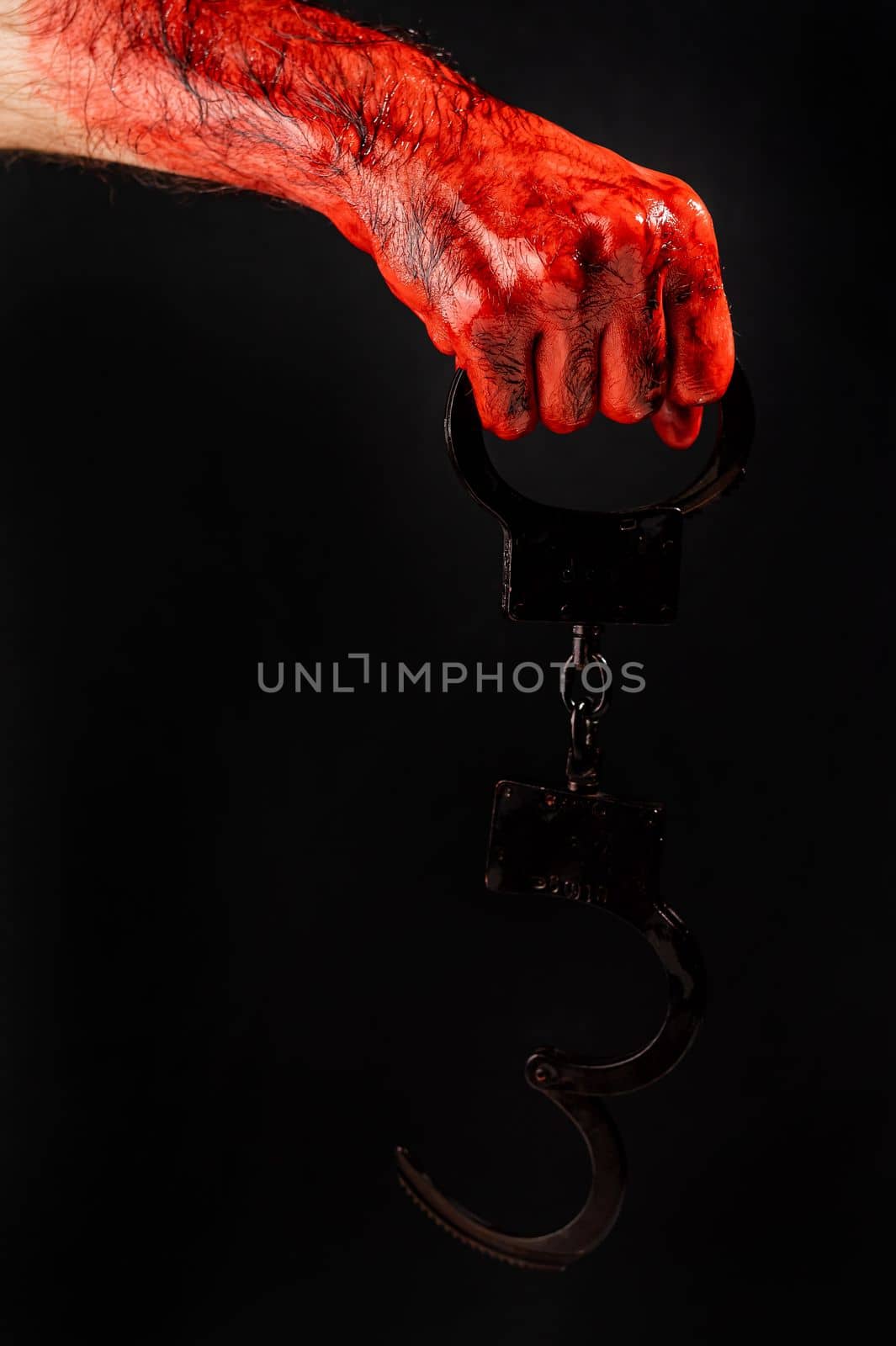 Faceless man holding handcuffs black background. Hands are stained with blood. by mrwed54