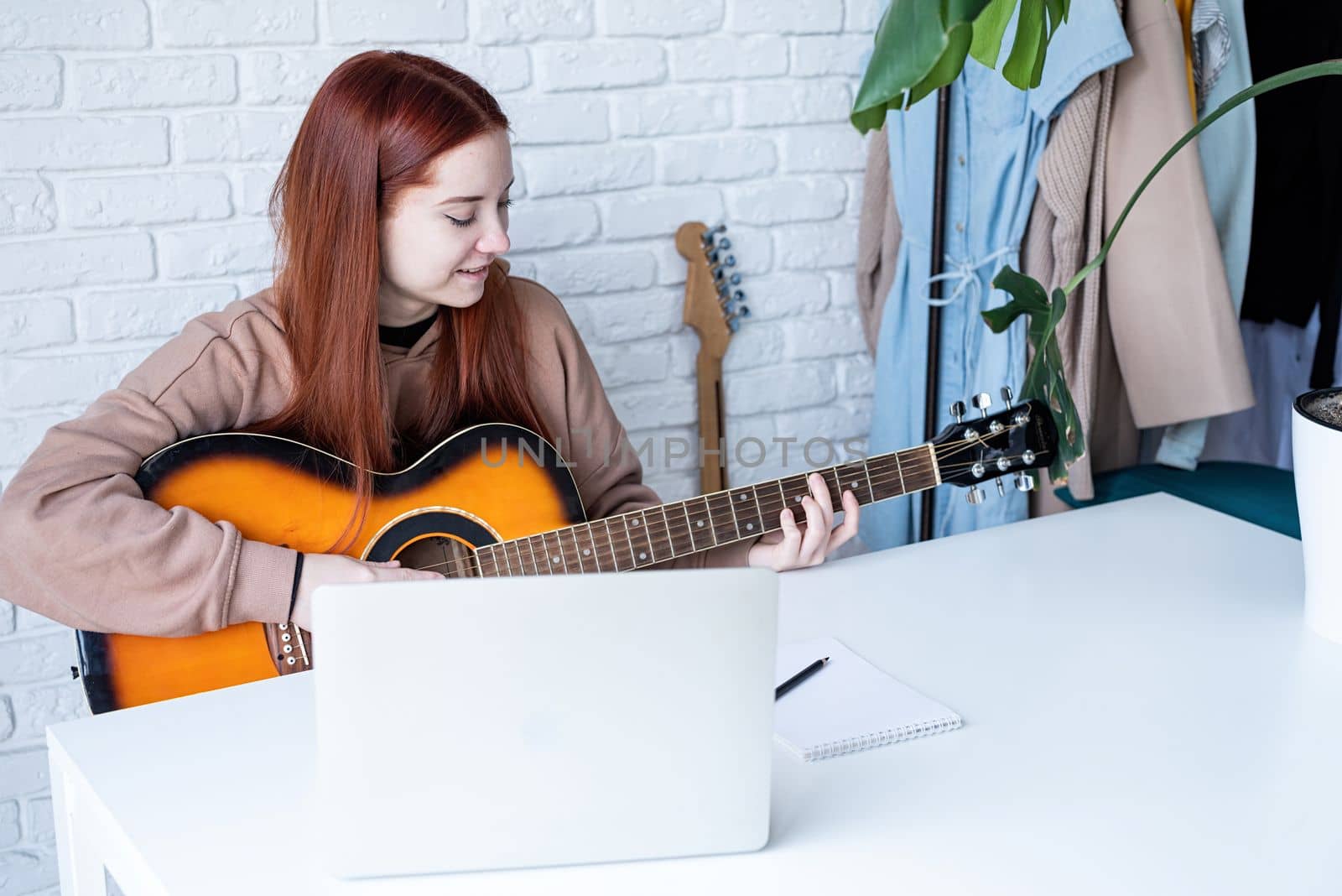 Young woman learning to play guitar at home by Desperada