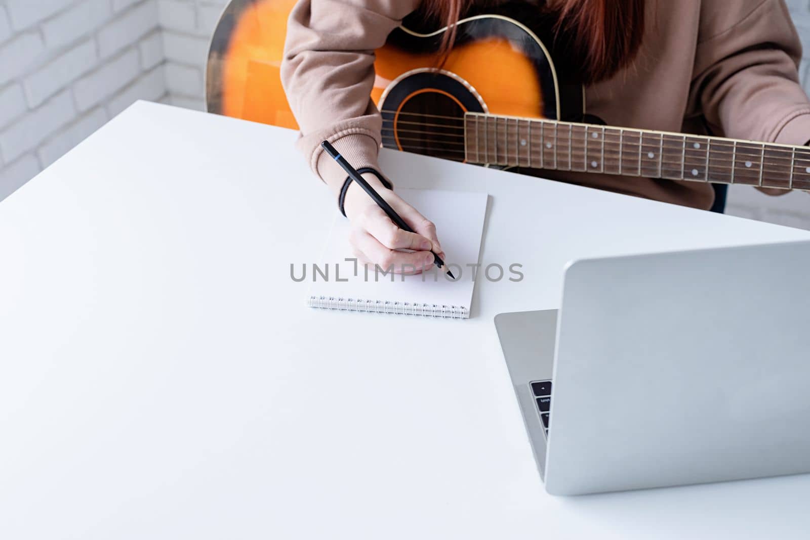 Young woman learning to play guitar at home by Desperada