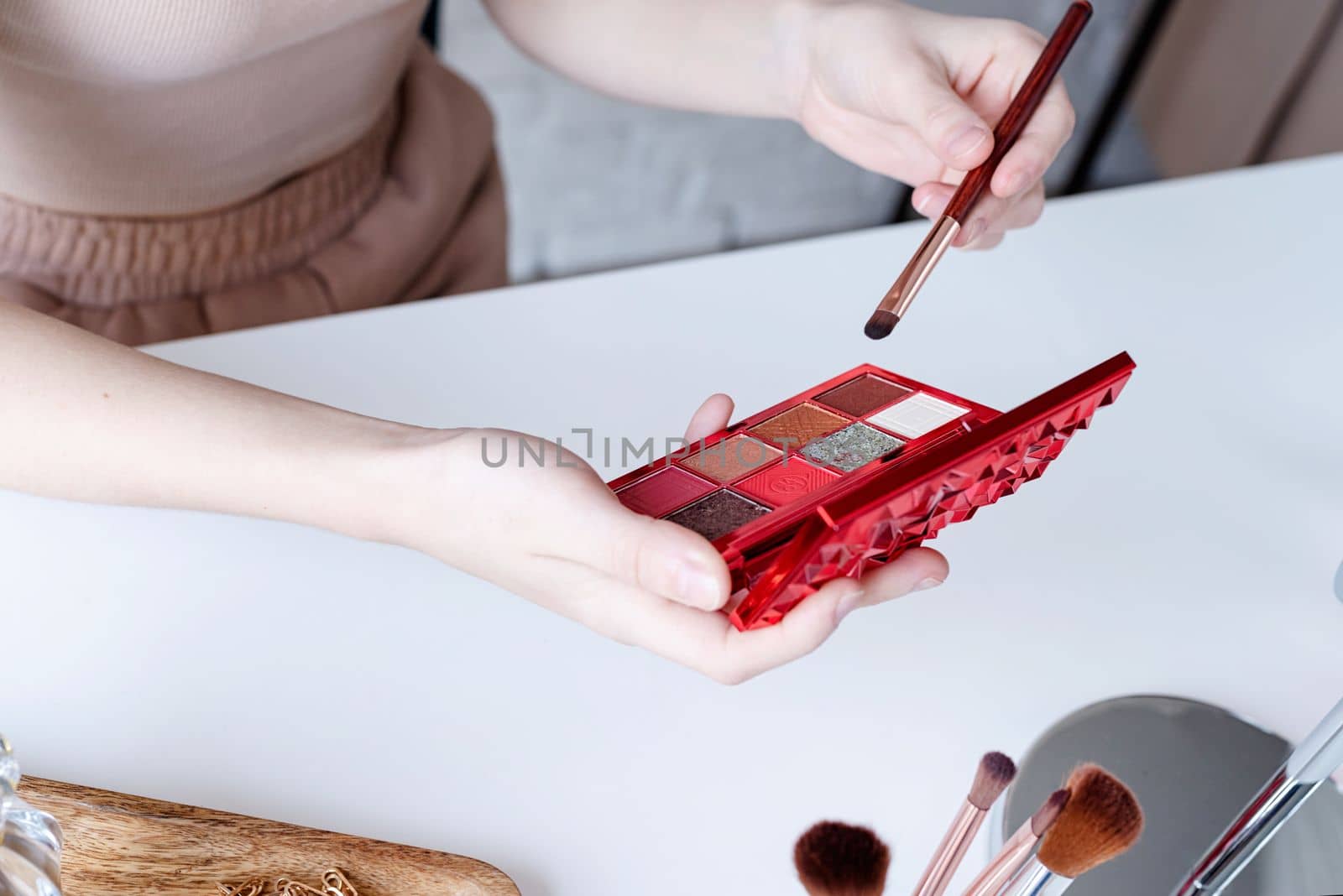 woman making up with cosmetics set at home. closeup of eyeshadow pallette with vivid colos in woman hand