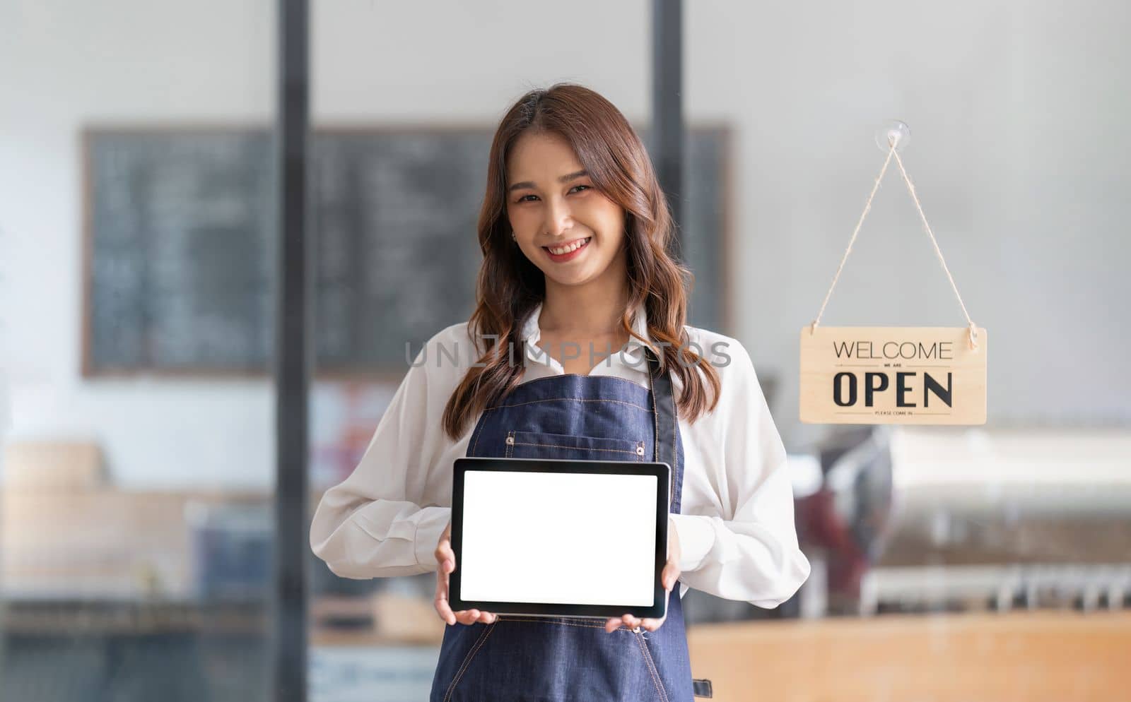 portrait of a woman wearing an apron holding a digital tablet with a blank white screen. Waiter holding a touch screen tab with copy space for your text