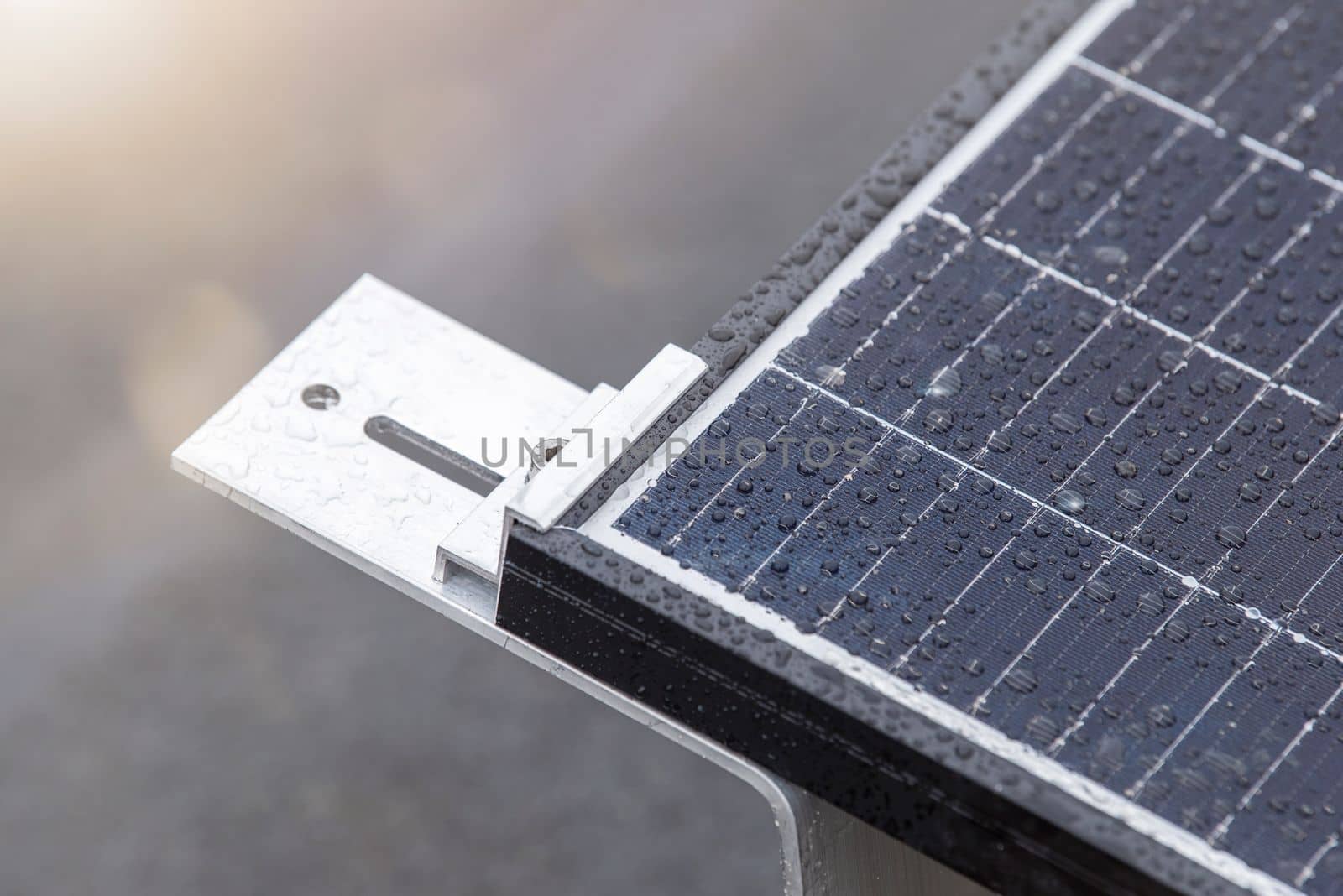 Bracket for mounting solar panels. Mounting a solar panel close-up on the roof of a residential building, water drops after rain, green energy production
