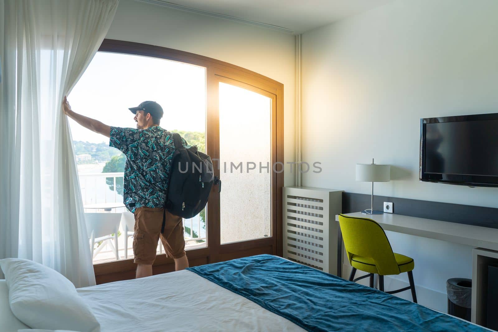 Tourist man in the hotel bedroom with her luggage standing near the window. Travel and vacation concept. by PaulCarr