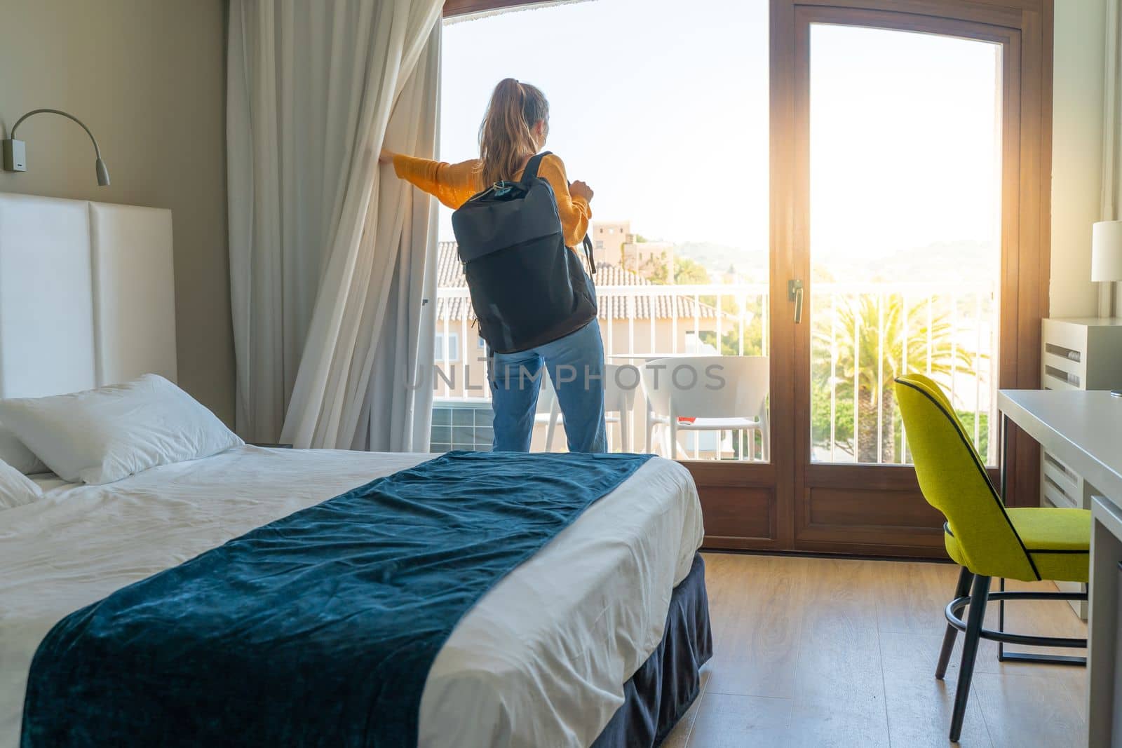 Tourist woman in the hotel bedroom with her luggage standing near the window. Travel and vacation concept. High quality photo
