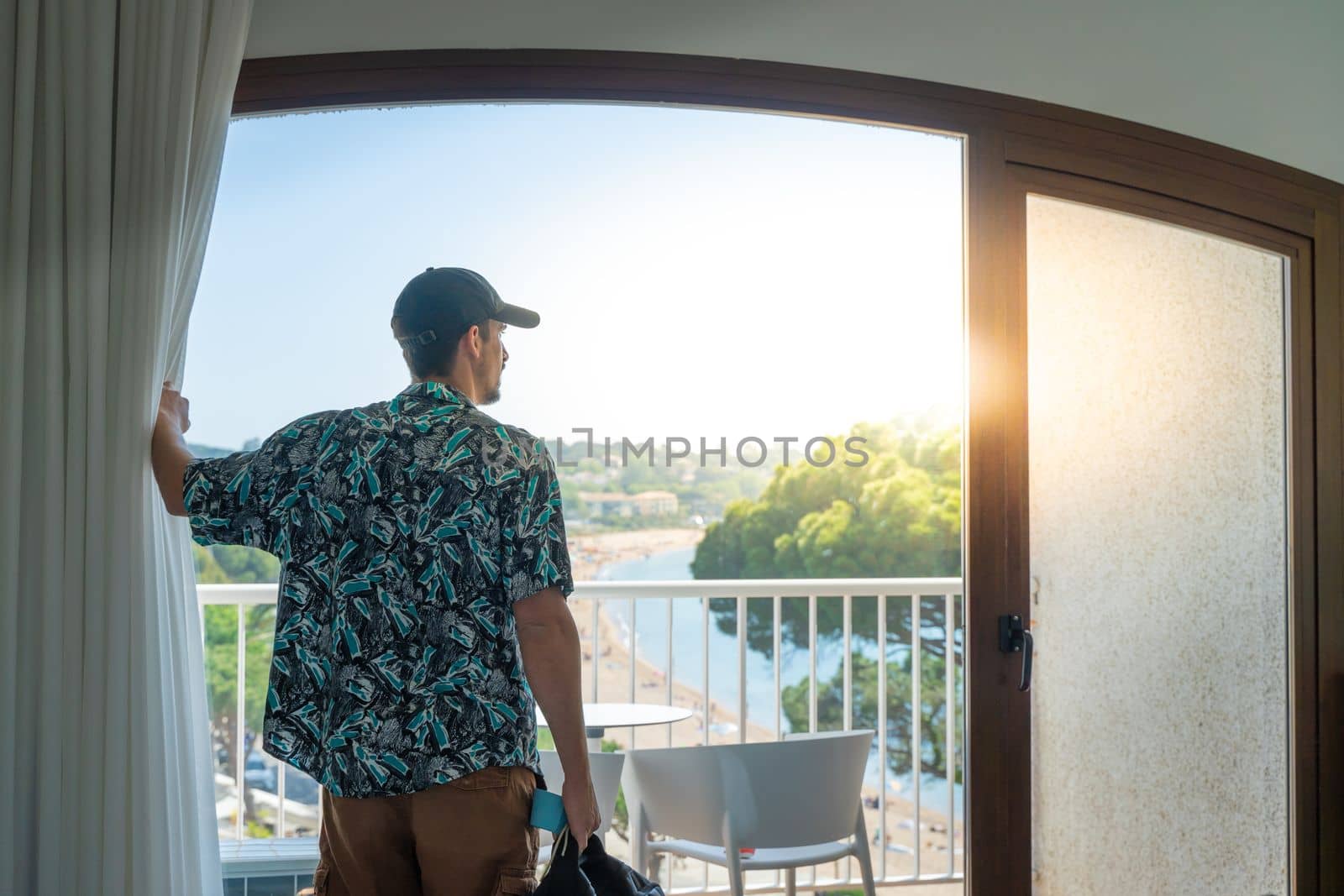 Tourist man in the hotel bedroom with her luggage standing near the window. Travel and vacation concept. High quality photo