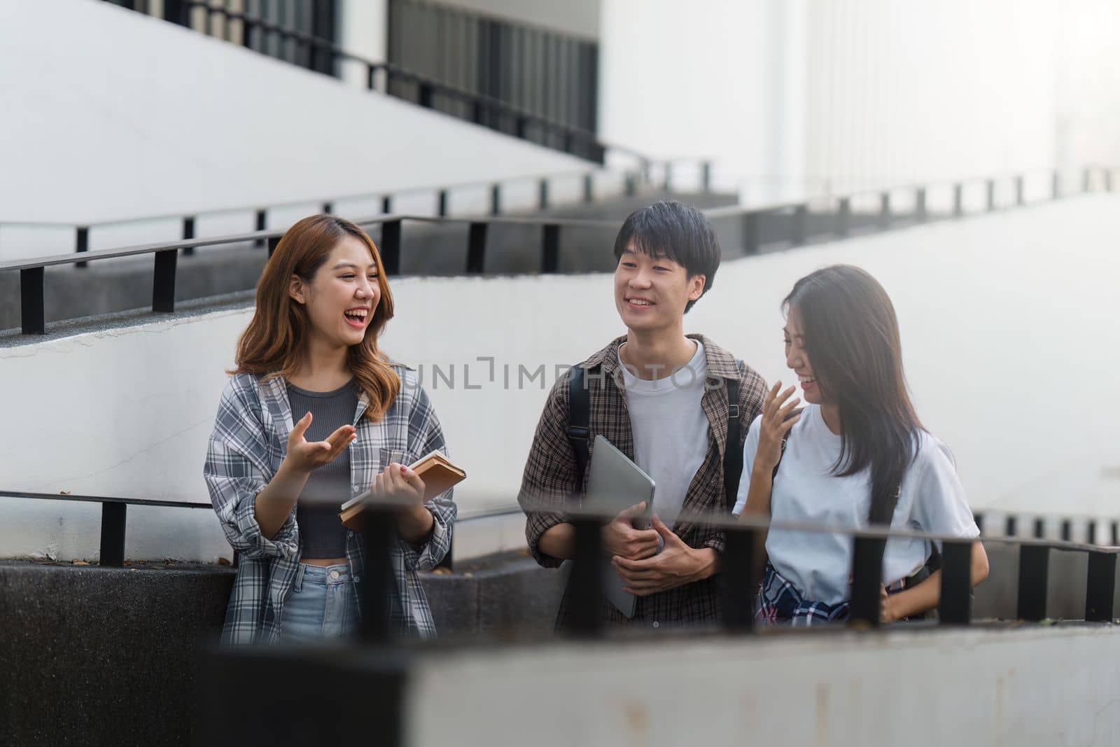 Beautiful young Asian woman college student with friends at outdoors. College student working on the college campus.