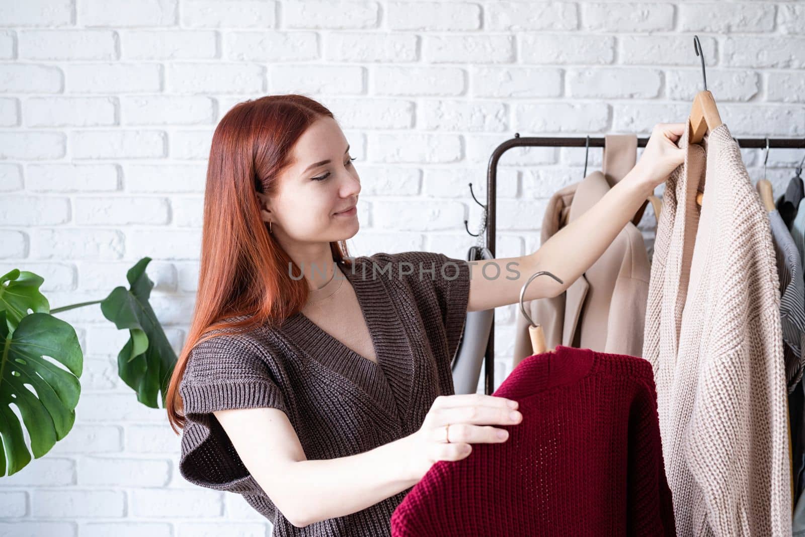 young beautiful woman wearing trendy outfit, standing near clothes rack choosing clothes. Wardrobe change by Desperada