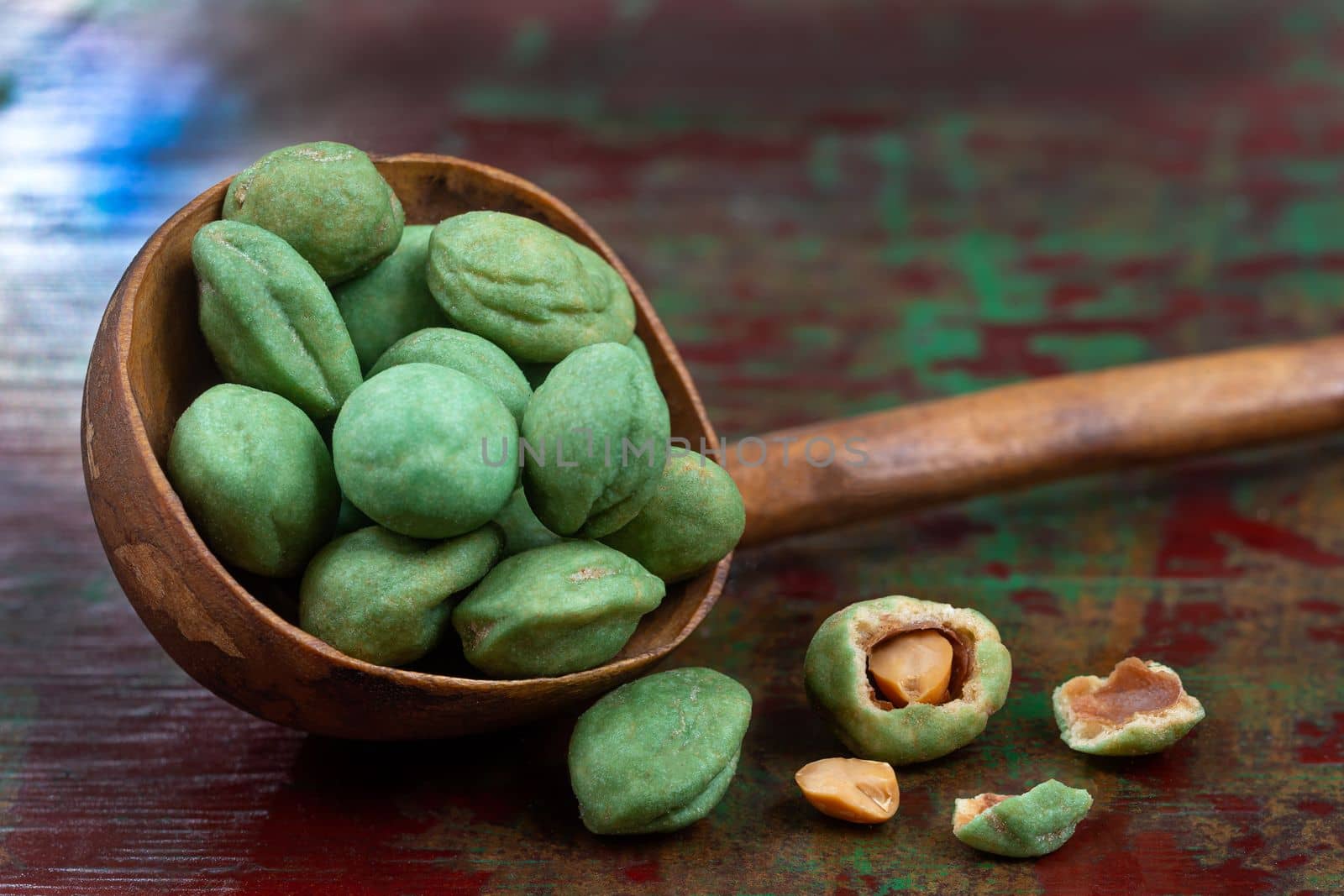 Pile of wasabi coated peanuts isolated on wooden ladle green and brown background by JPC-PROD