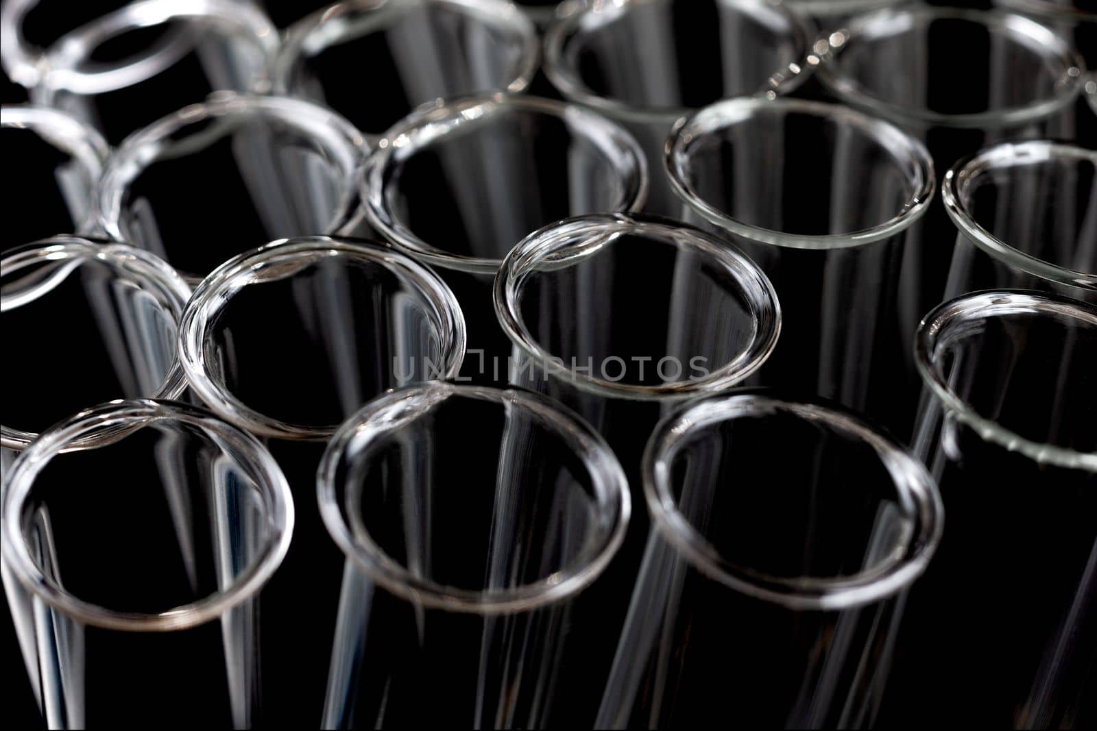 Closeup of many empty glass test tubes on a dark background. Toned image.