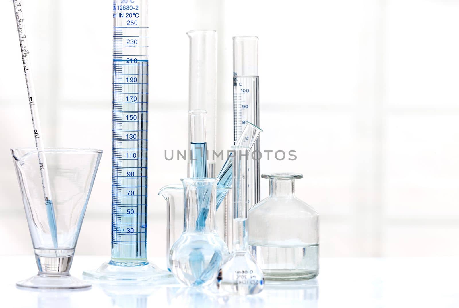 Set of laboratory glassware with blue liquid on white background. B