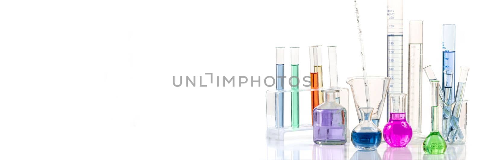 Laboratory equipment and color chemicals on white background