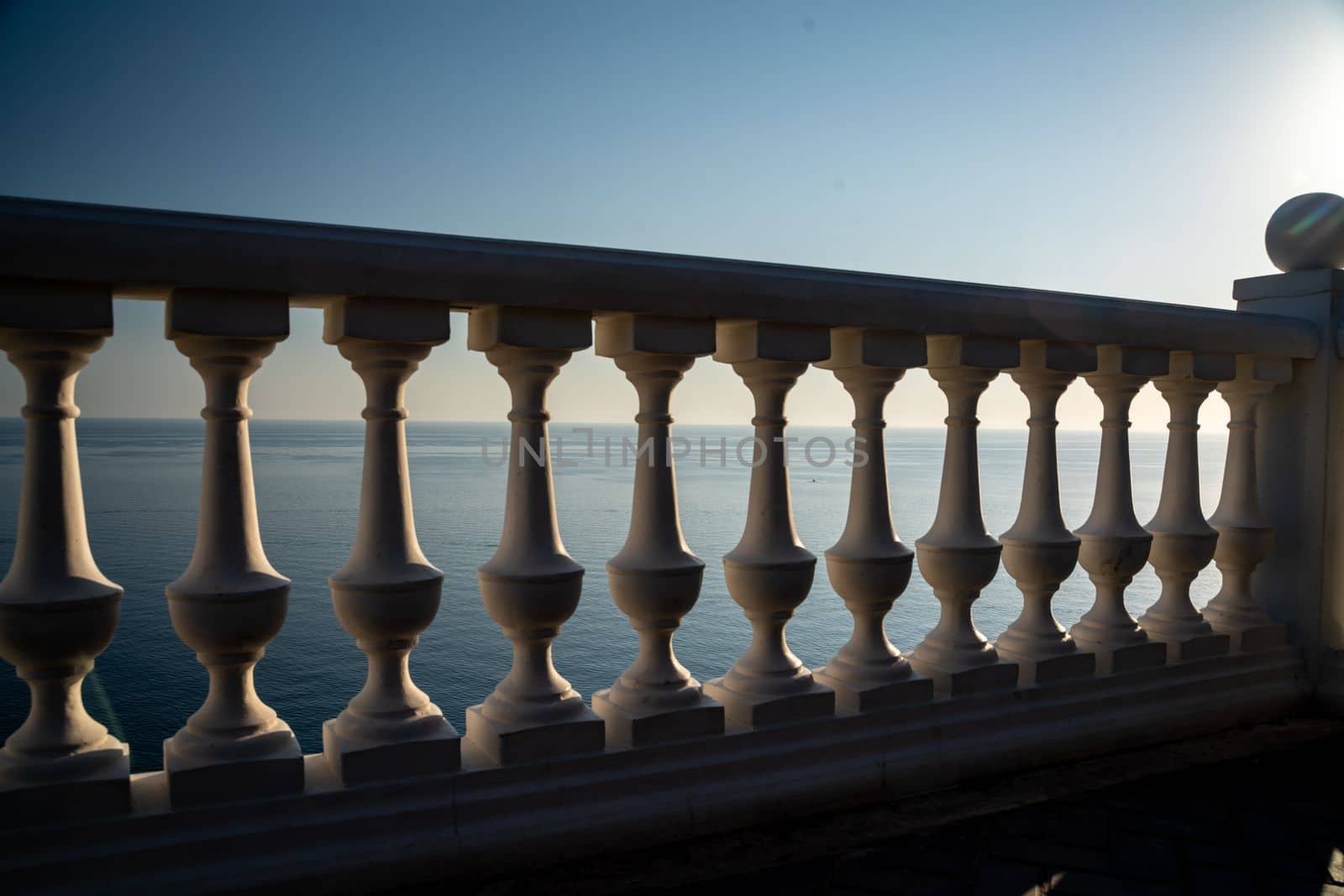 Classic balustrade on the embankment against the sea. White balcony over the sea. Promenade with a beautiful view of the sea on a clear day. Close-up of the balustrade by the sea.