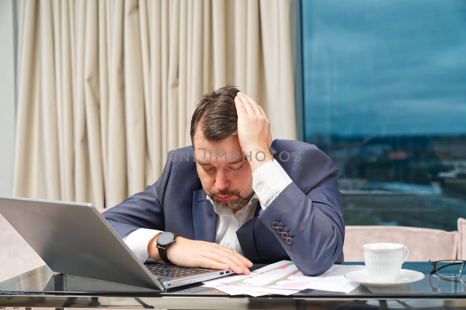 Tired man working at home office, Exhausted, stressed, overworked man, financial market decline, unsuccessful investments. tension headache. Sad businessman lying on laptop.