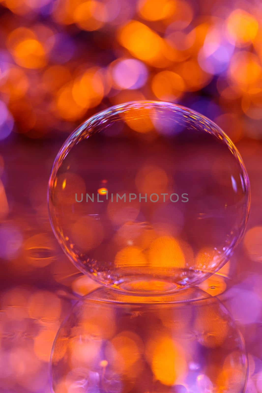 A soap bubble lies on the surface of the water with a red-orange background