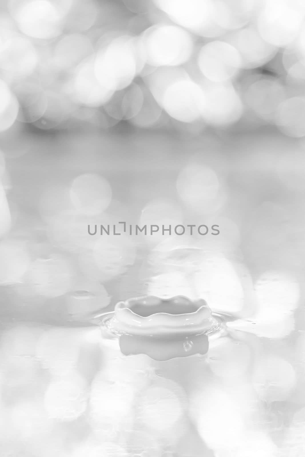 The drop falls into a dense liquid with a white background. Abstract colorful background