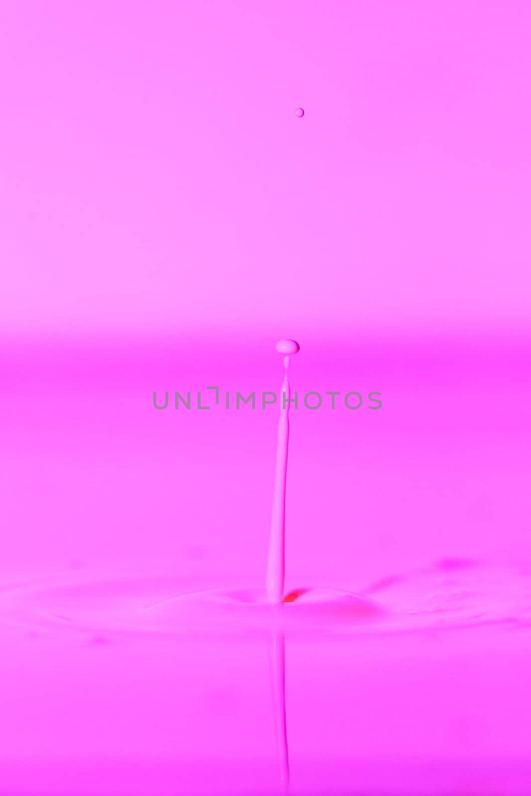 A drop falls into a thick liquid with a pink background. Abstract colorful background. by Yurich32
