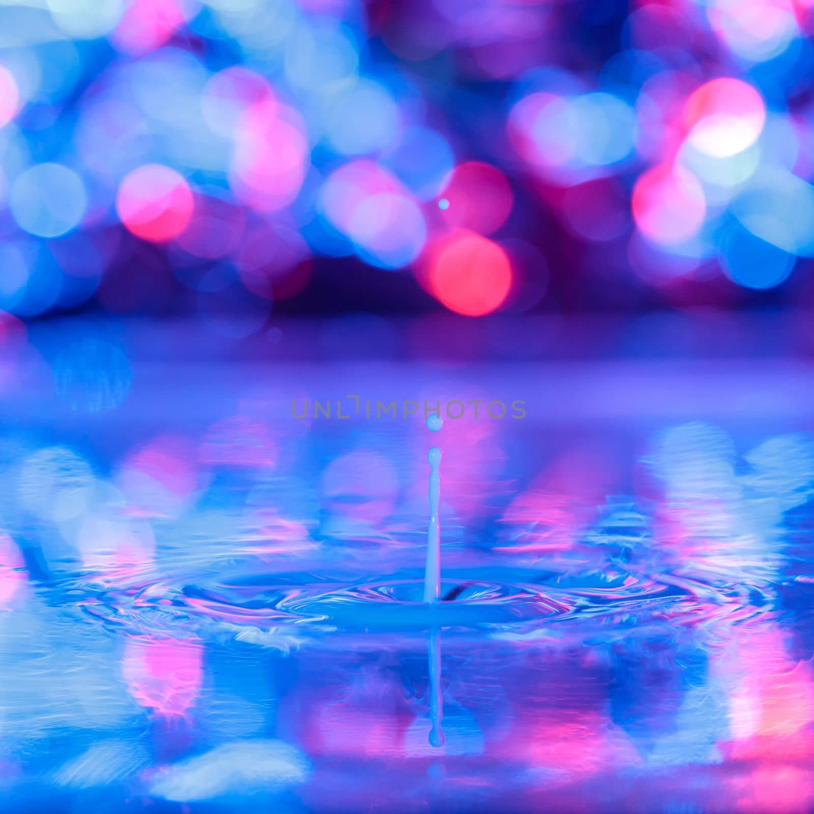 A drop falls into a thick liquid with a blue-violet background. Abstract colorful background. by Yurich32