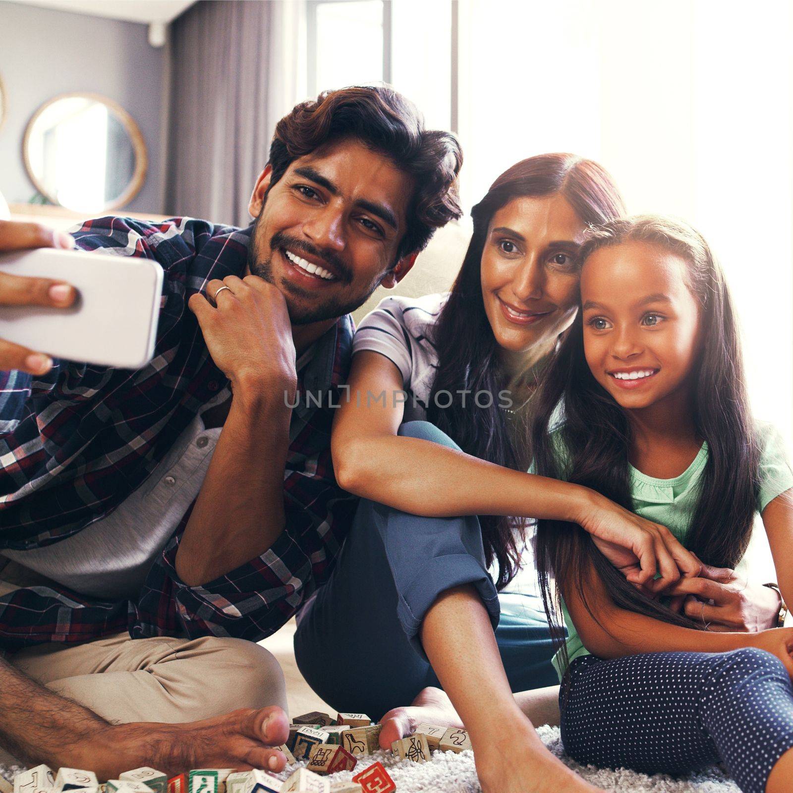 Capturing family photos is capturing cherished moments. a young family taking a selfie at home. by YuriArcurs