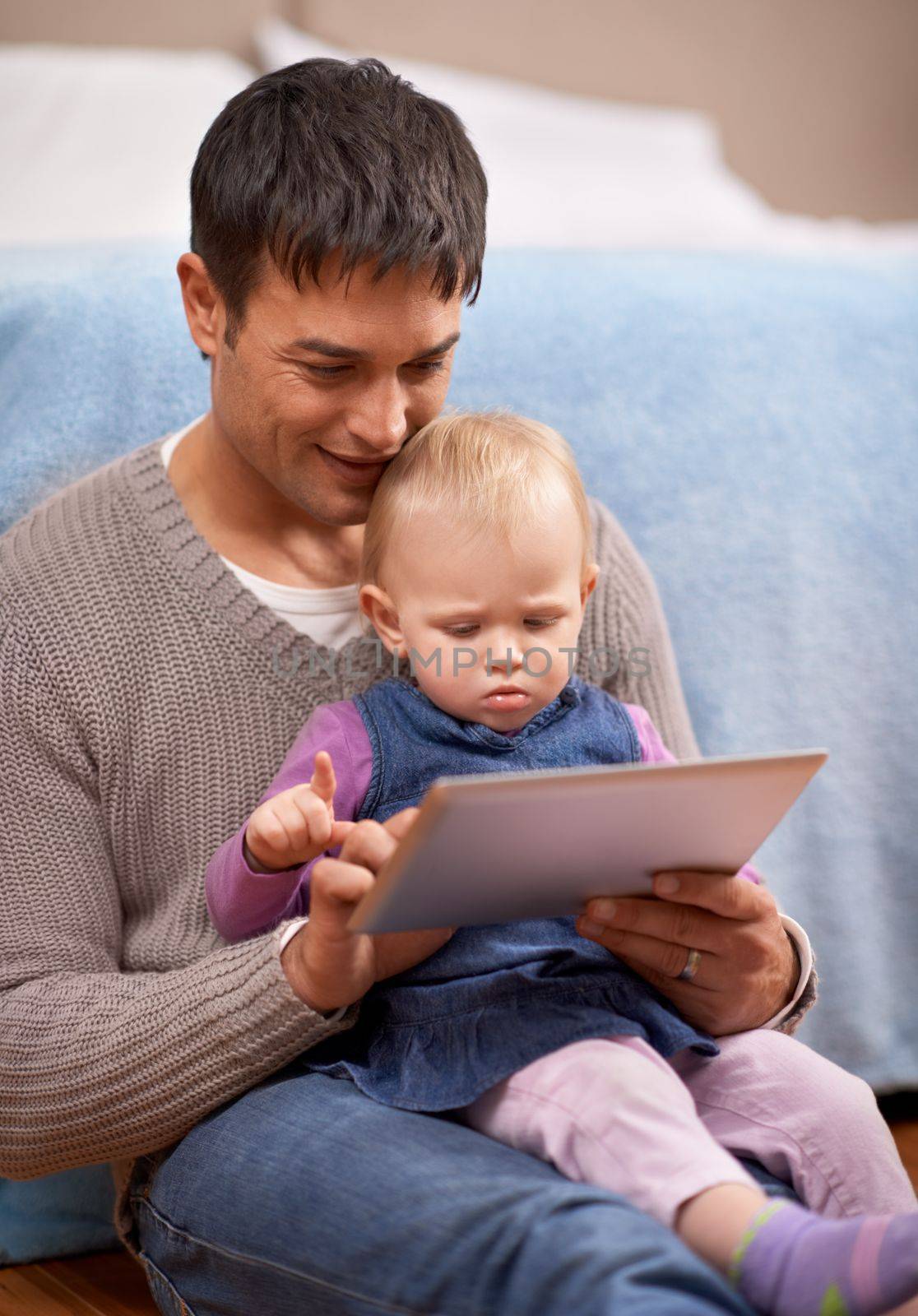 Showing dad how its done. A young father showing his baby girl something on a digital tablet. by YuriArcurs