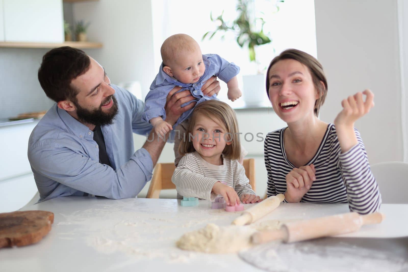 Happy parents playing with their children in the kitchen