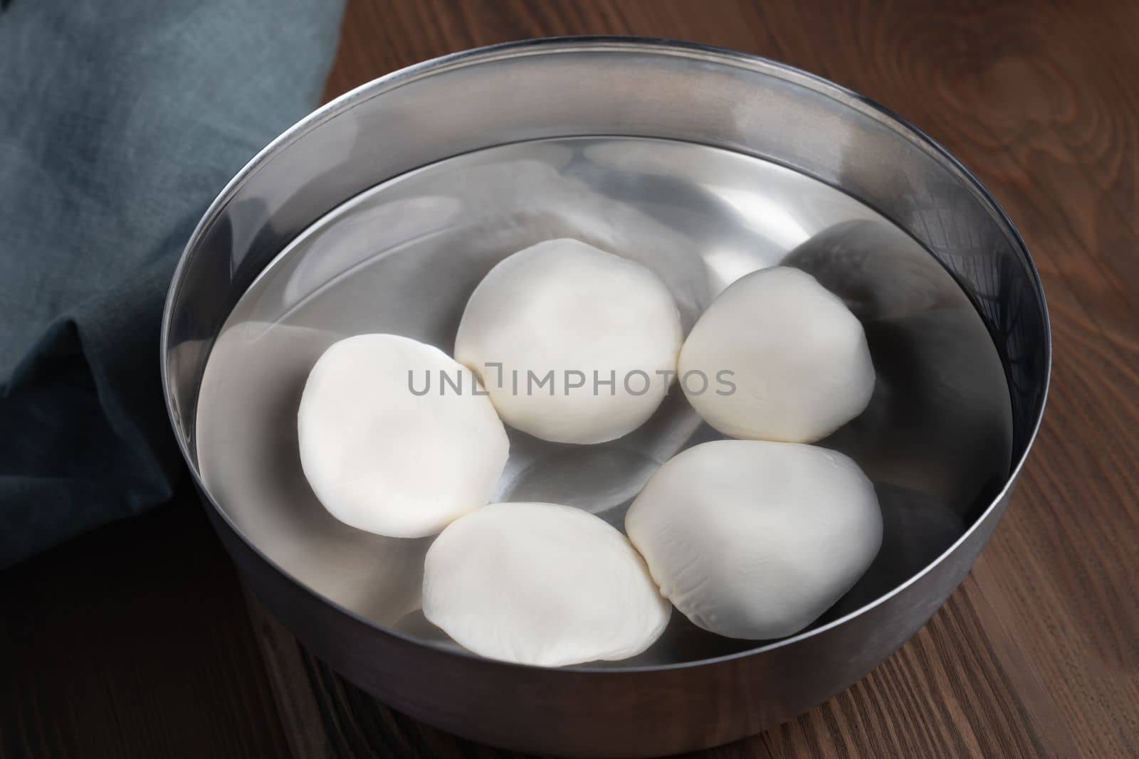 Making mozzarella cheese. Cooling the finished balls in cold water by galsand