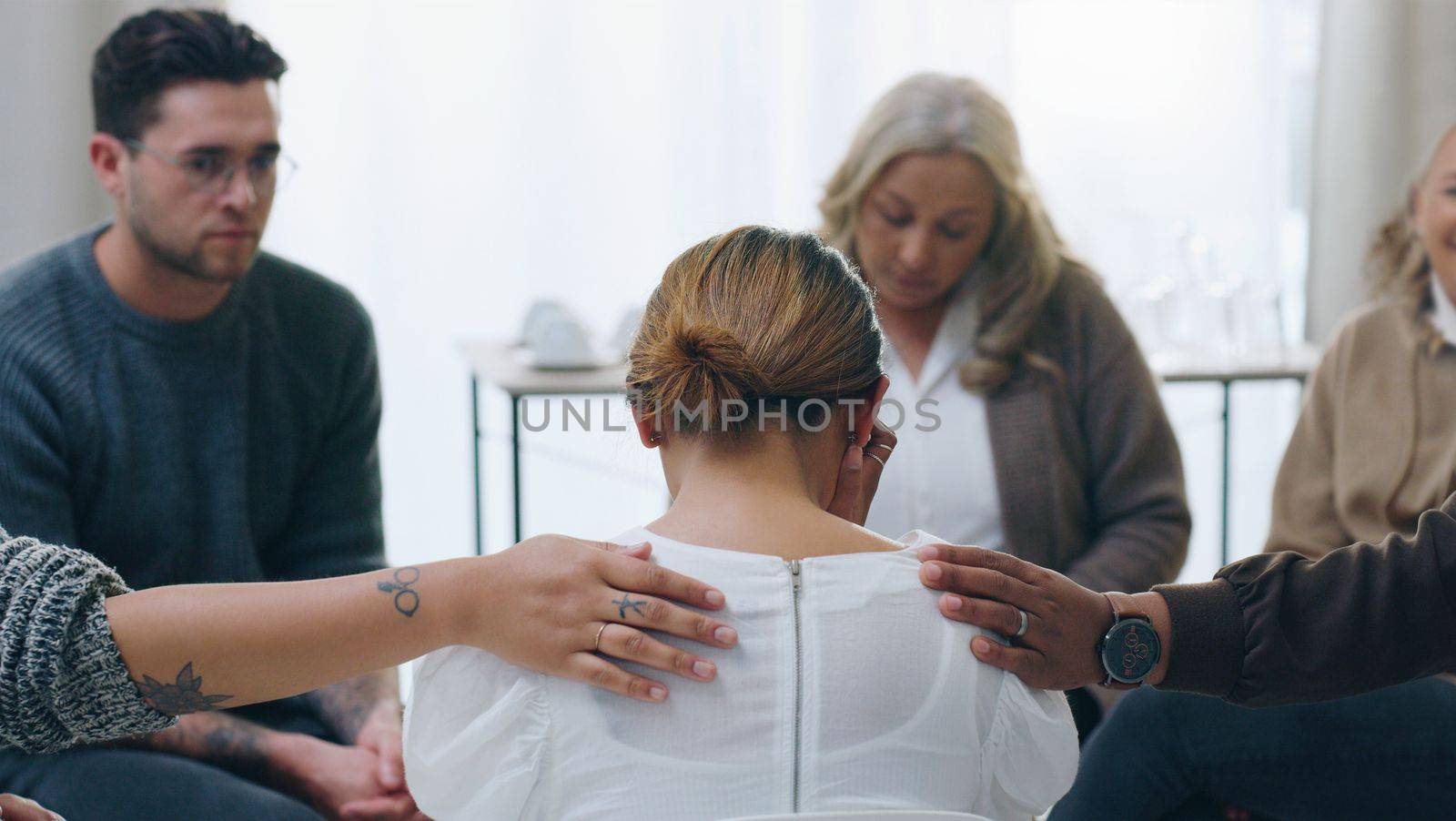 Group therapy, meeting and counseling with people in support to console a woman patient during a session for health. Community, mental health and counselling with a female taking about her emotions by YuriArcurs