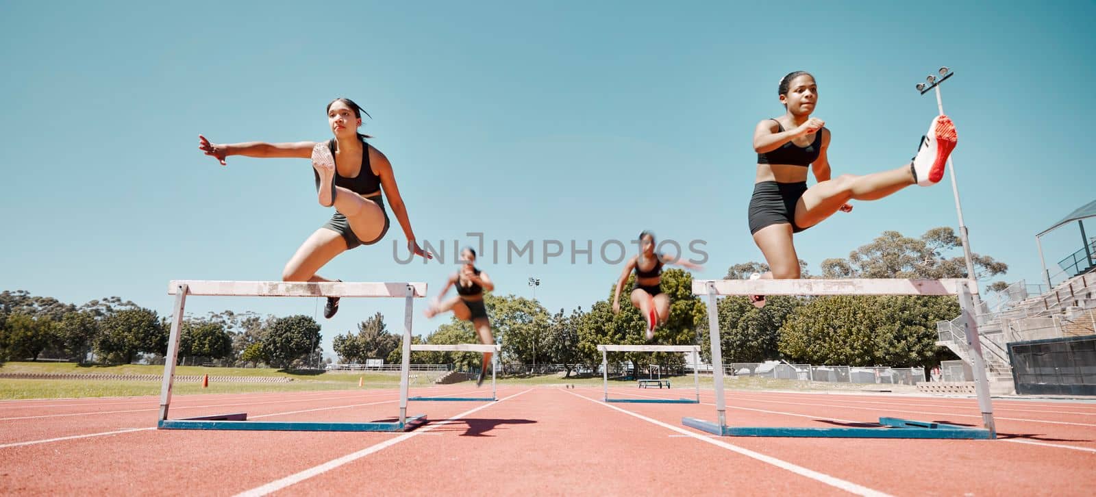 Woman, jumping and hurdles in competitive sports training, exercise or athletics on the stadium track. Women in sport fitness competition for hurdle jump, running and fast cardio exercising outside by YuriArcurs