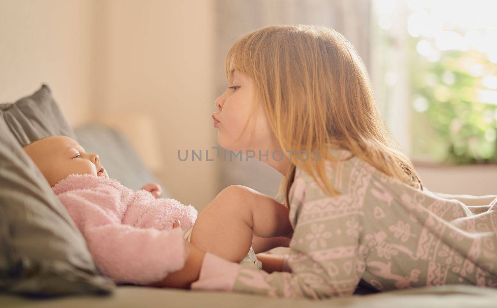 There is no better friend than a sister. a cute little girl playing with her baby sister on a bed