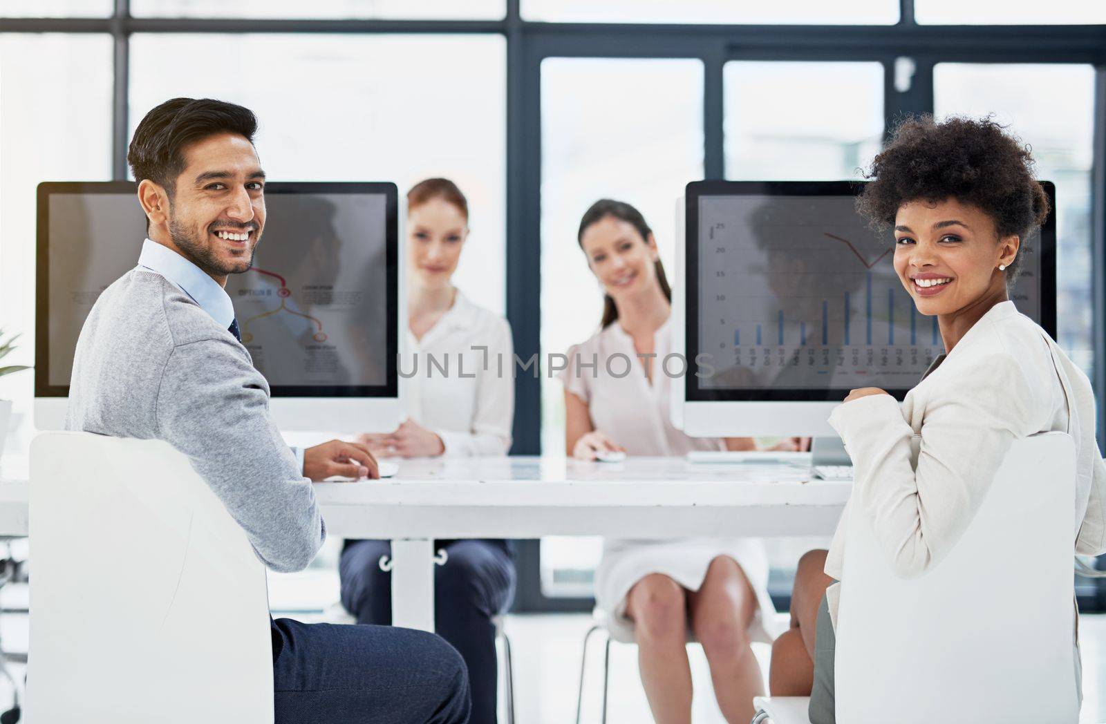 Technology is the spine of our business. Portrait of a group of businesspeople working at their desks. by YuriArcurs