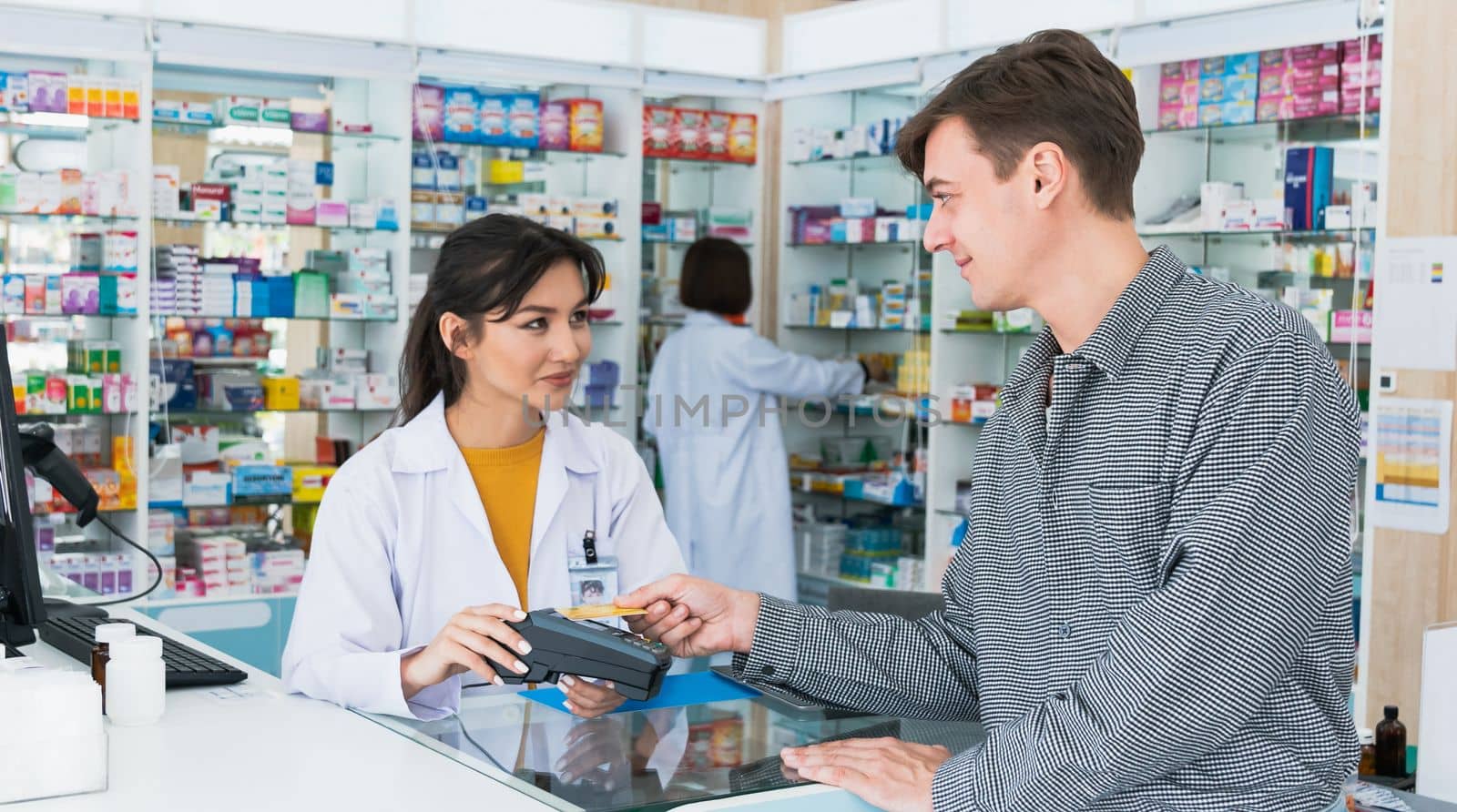 Payment by credit card with payment terminal in qualified drugstore. Modern financial payment of electric money. Caucasian customer purchase medication in pharmacy with prescription from pharmacist.