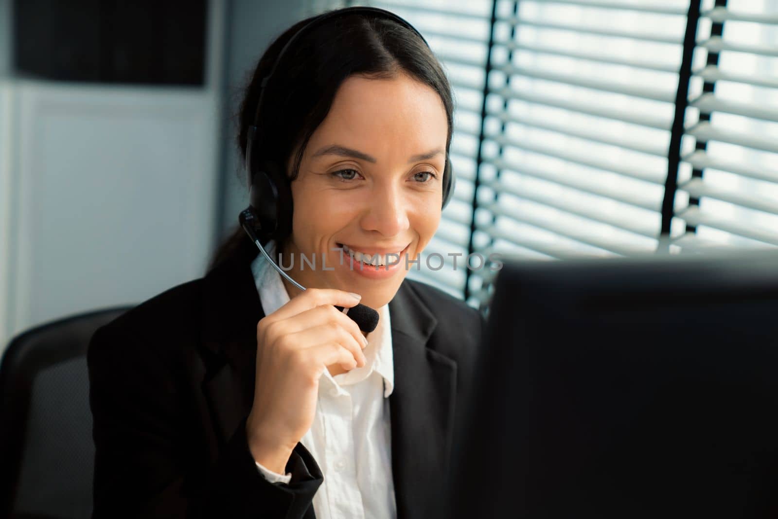 Competent female operator working on computer and talking with clients. Concept relevant to both call centers and customer service offices.