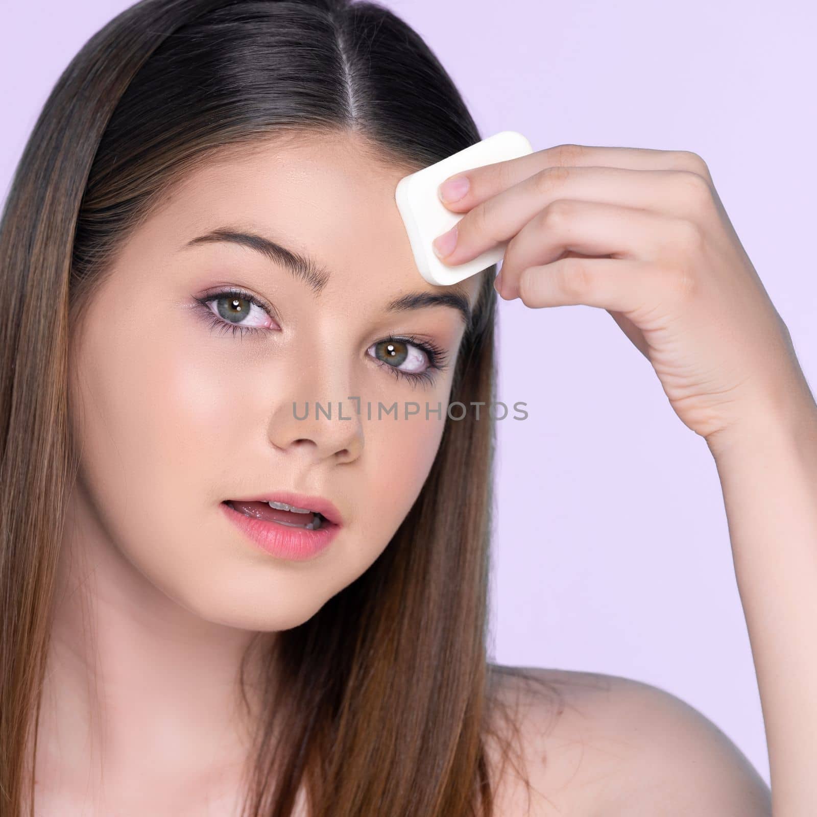 Portrait of young charming girl applying dry powder foundation on her face. by biancoblue